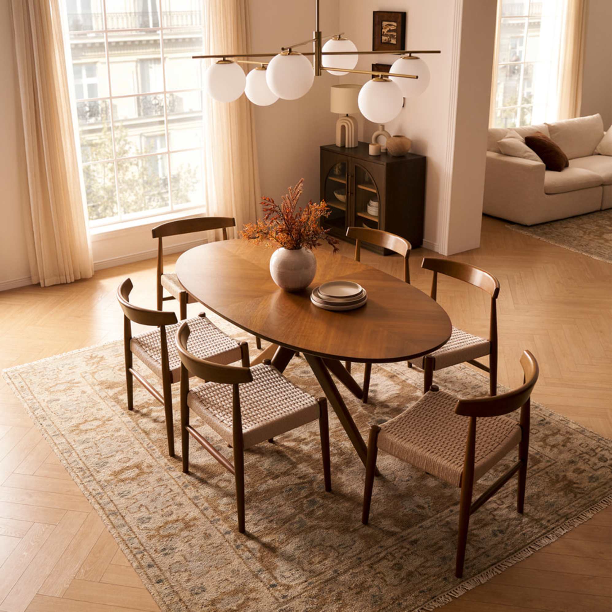 A wooden oval dining table with six armless dining chairs.