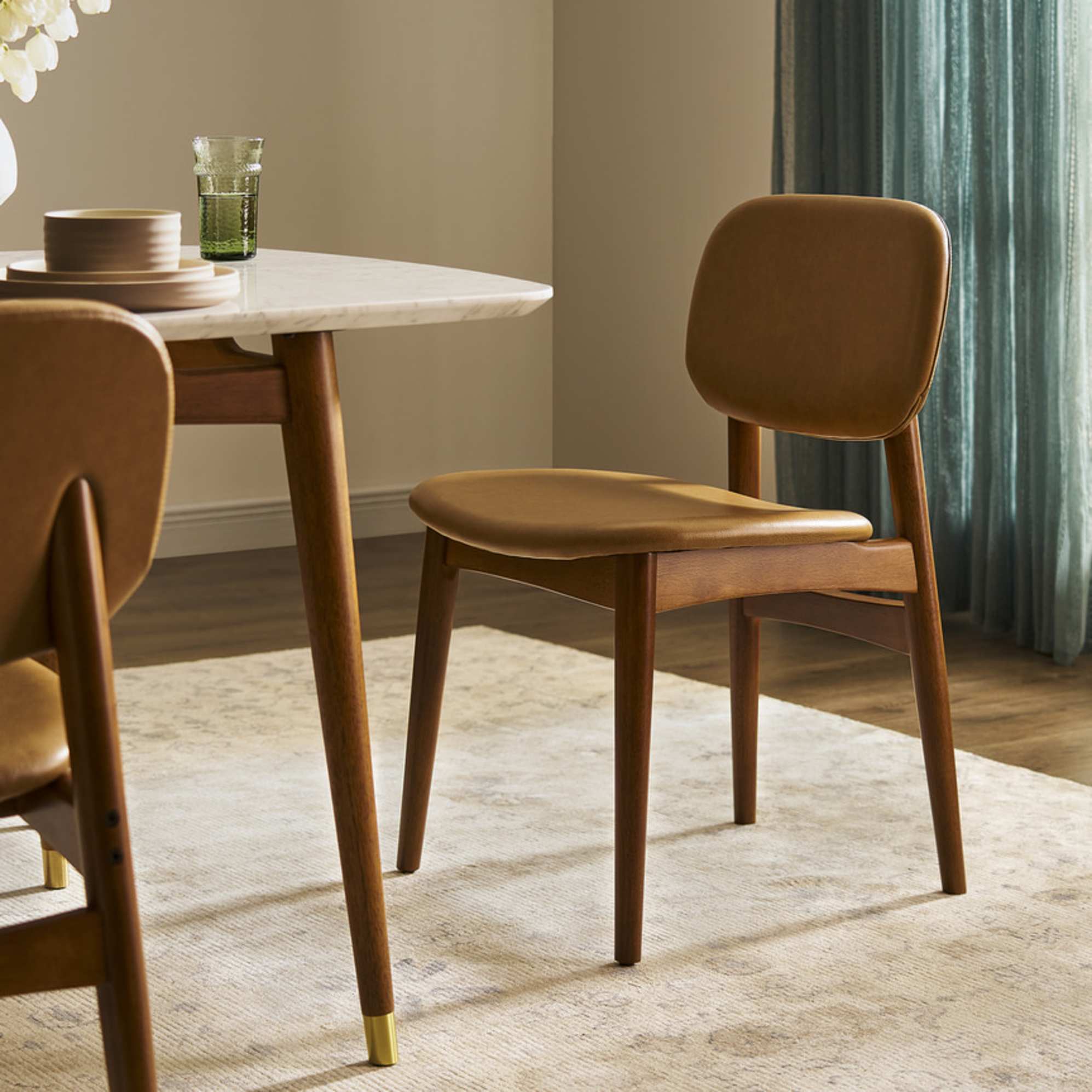 A close-up of a dining chair with a leather seat and back cushion.