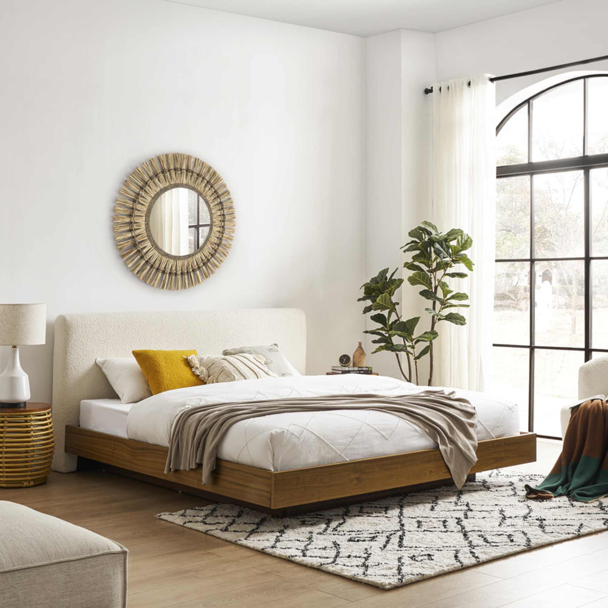 A bed with a bouclé headboard placed in a bedroom.