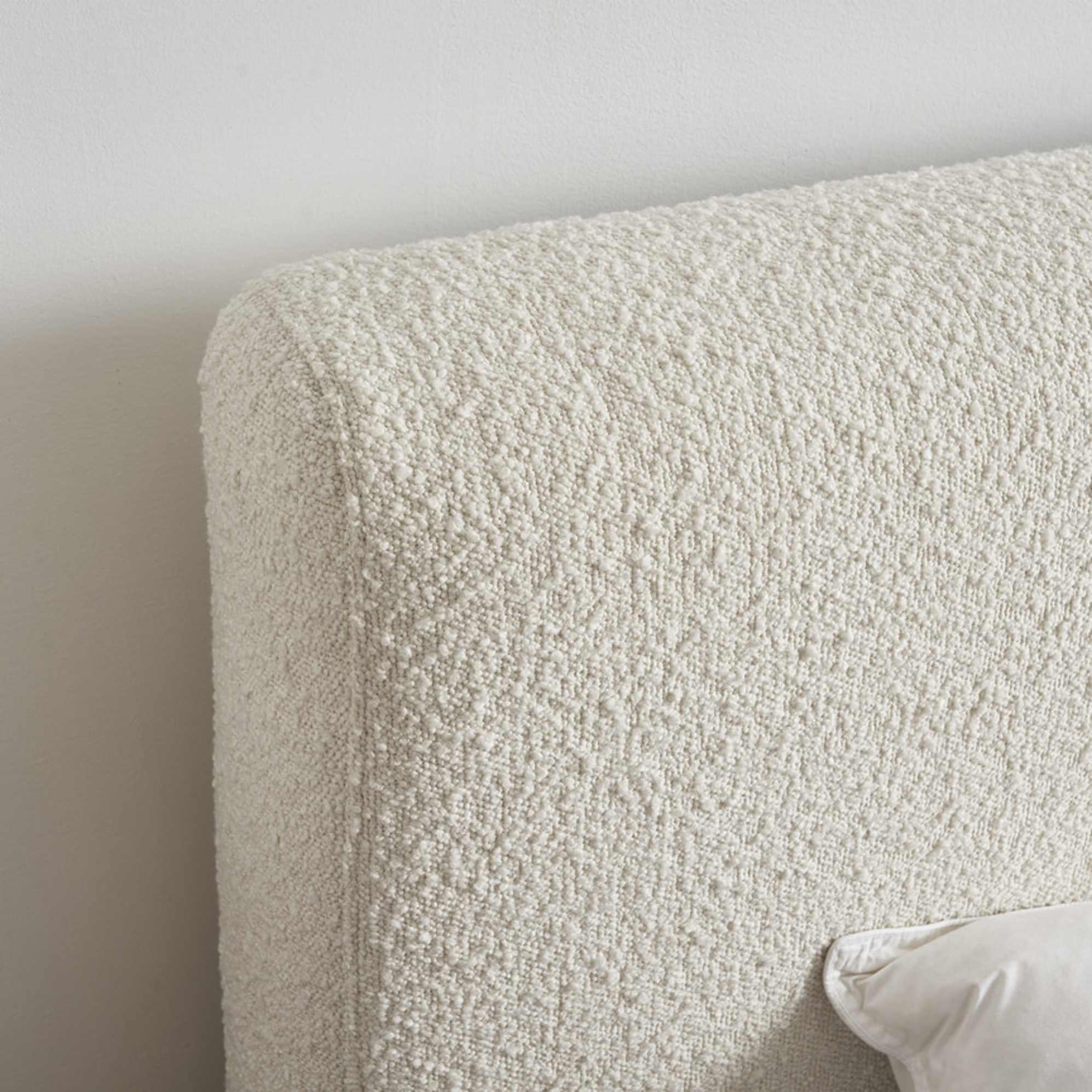A close-up of a bed upholstered in bouclé fabric.