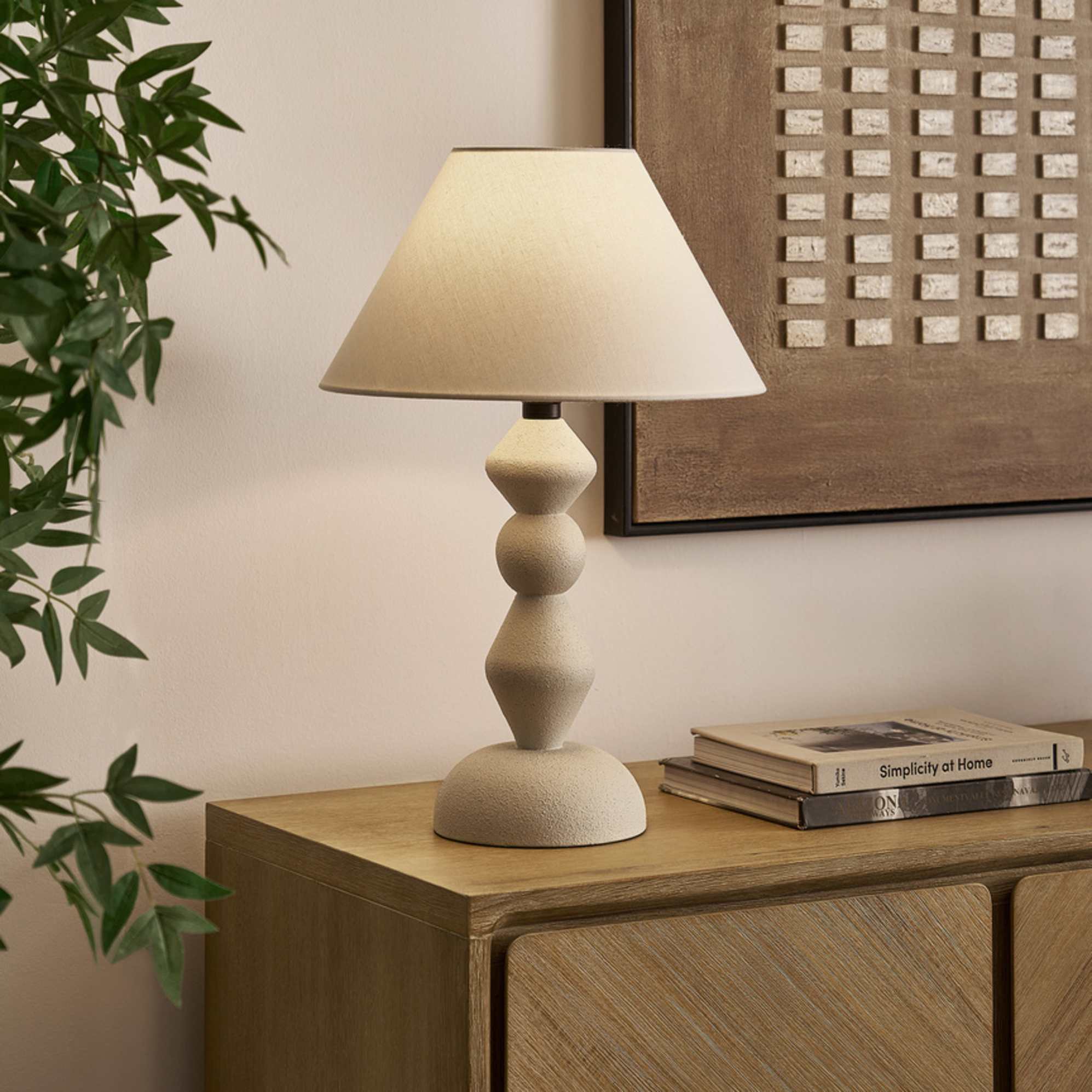 A table lamp with a geometric base placed on a side table.