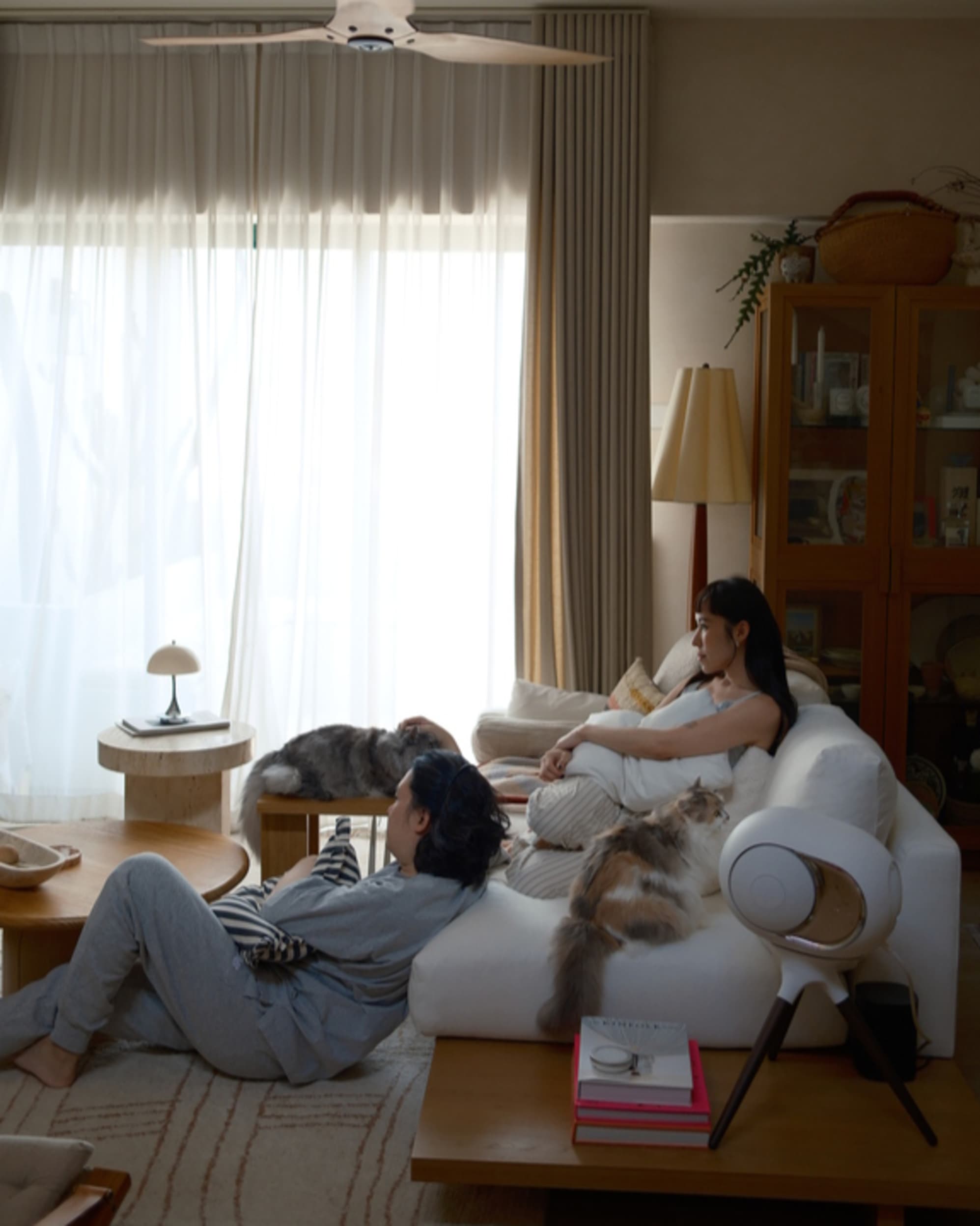 A woman sitting on a performance fabric sofa with a cat beside her, while a man leans against it while sitting on the floor.