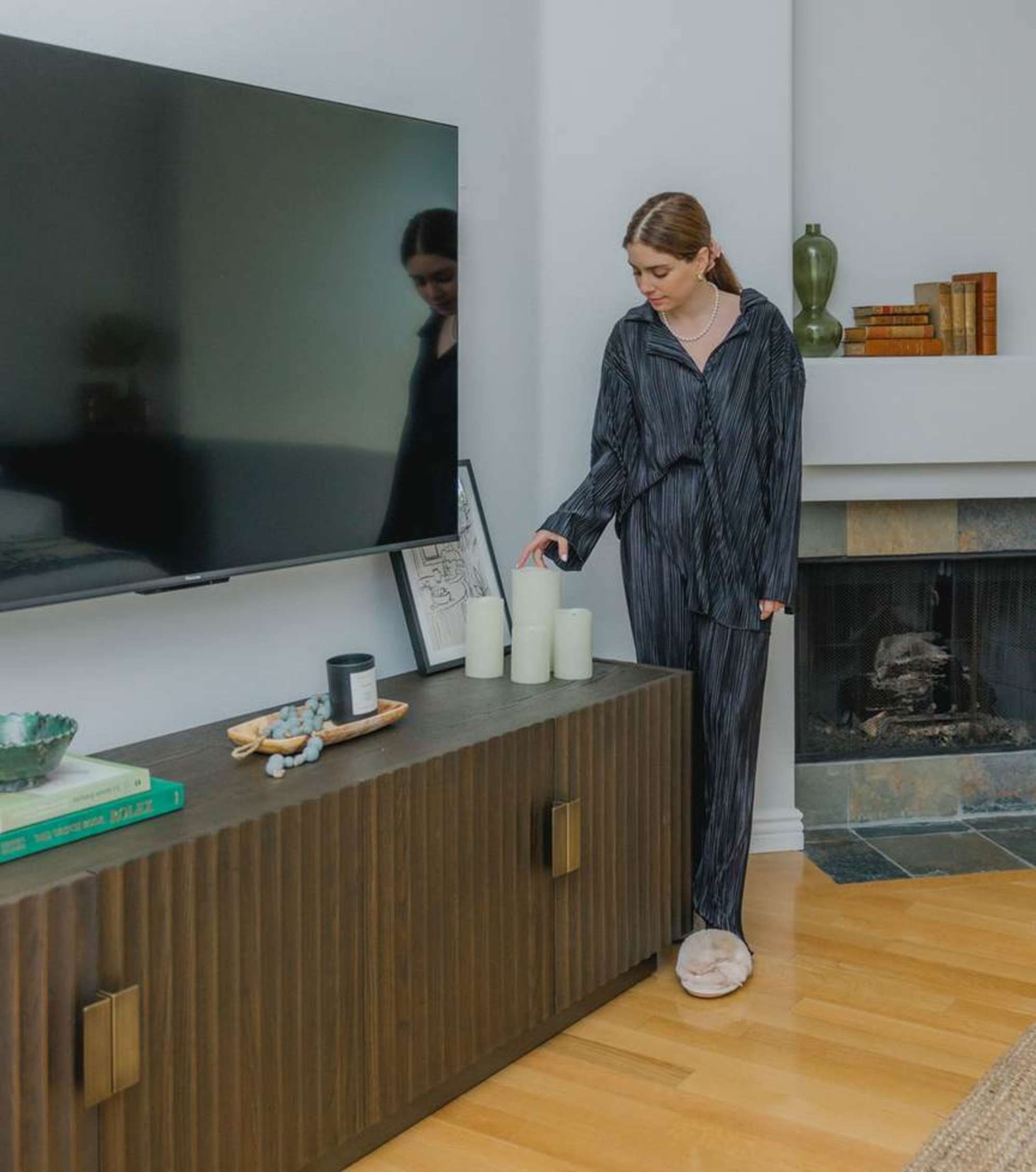 A person standing by a wooden TV stand. 
