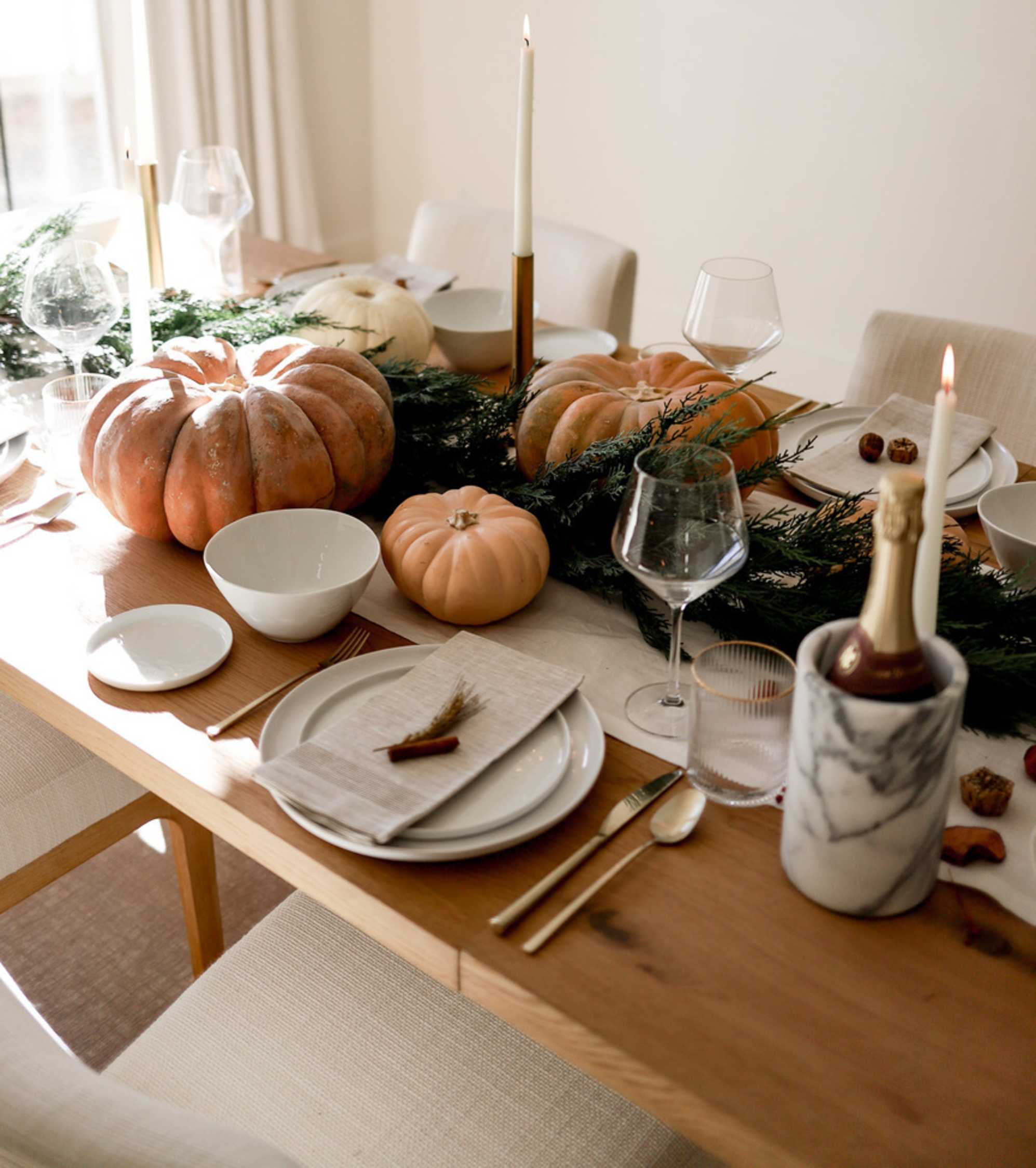 A wooden extendable dining table lined with fall decor and tableware.