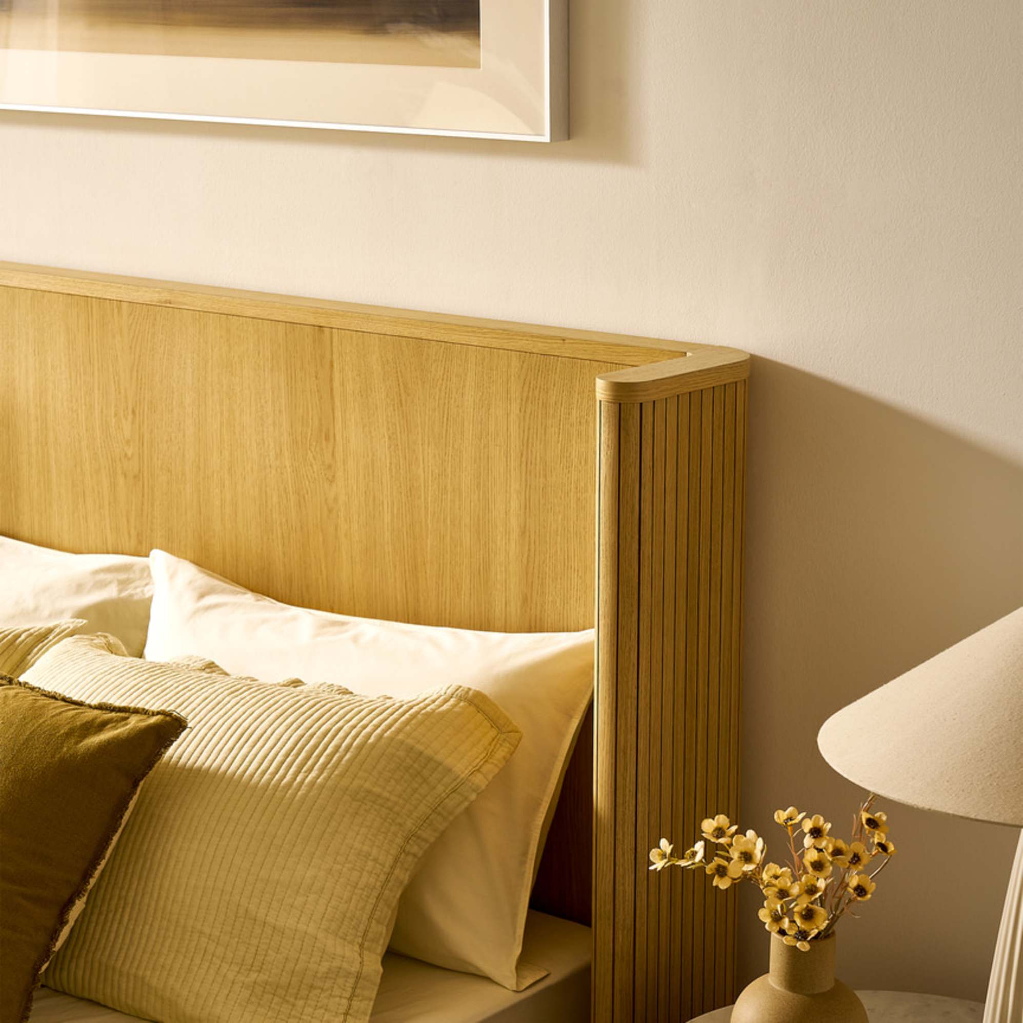 A close-up of a wooden bed with a wingback headboard.