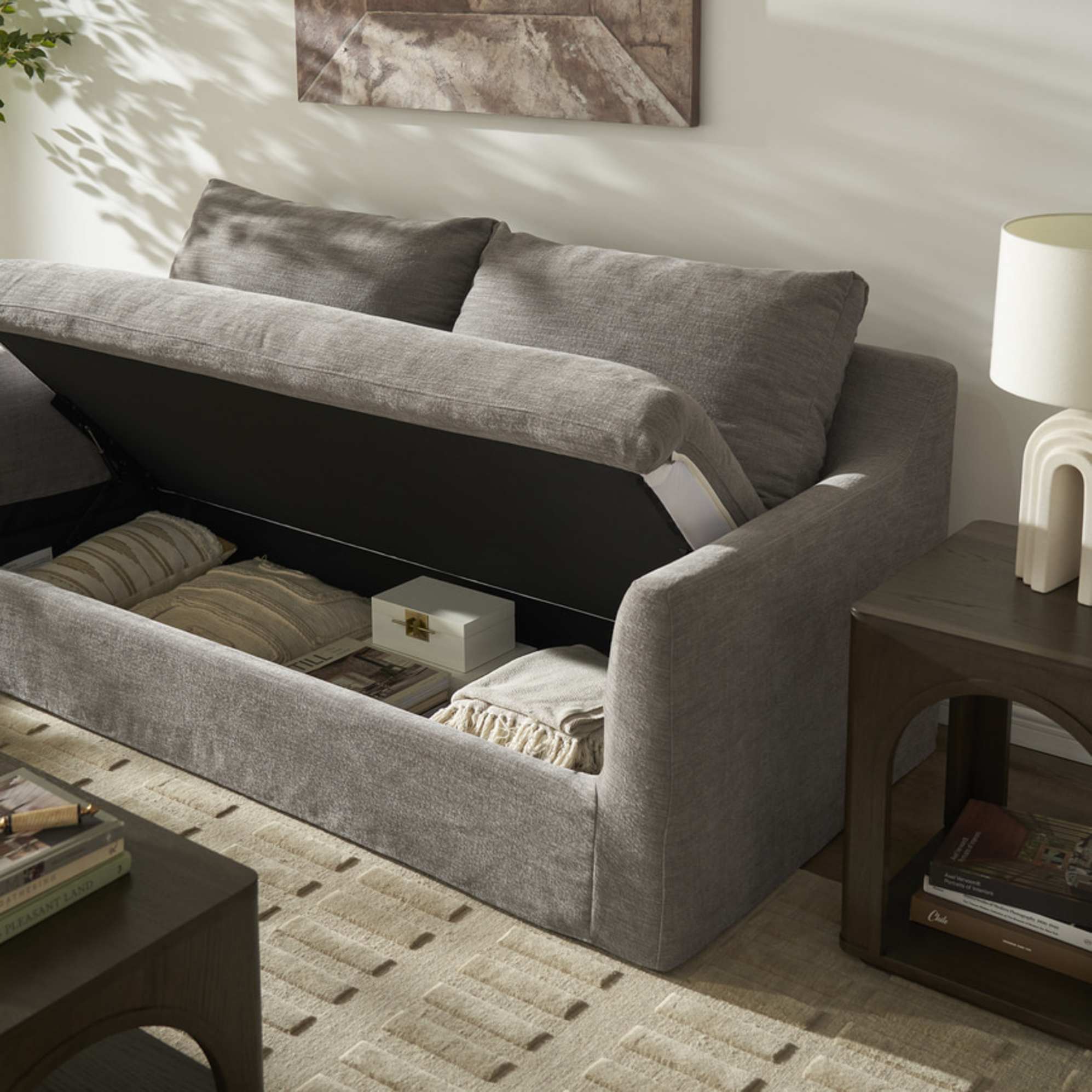 A slipcover 2-seater sofa with its seats lifted up to reveal hidden storage.