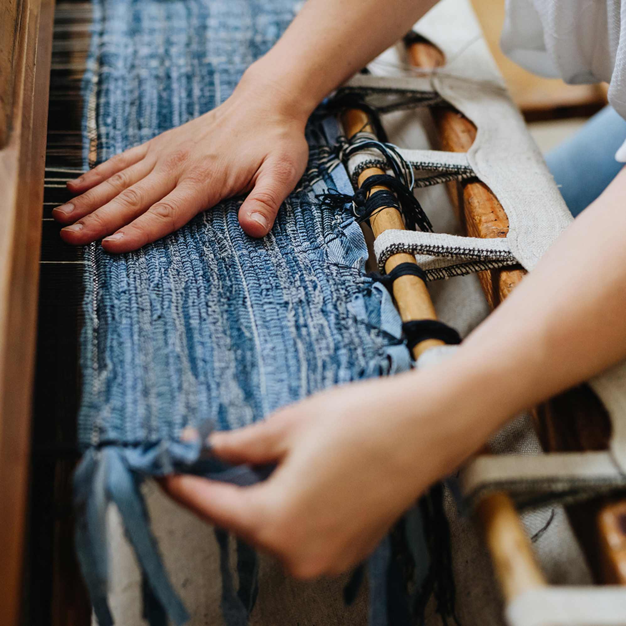 A person weaving a rug. 