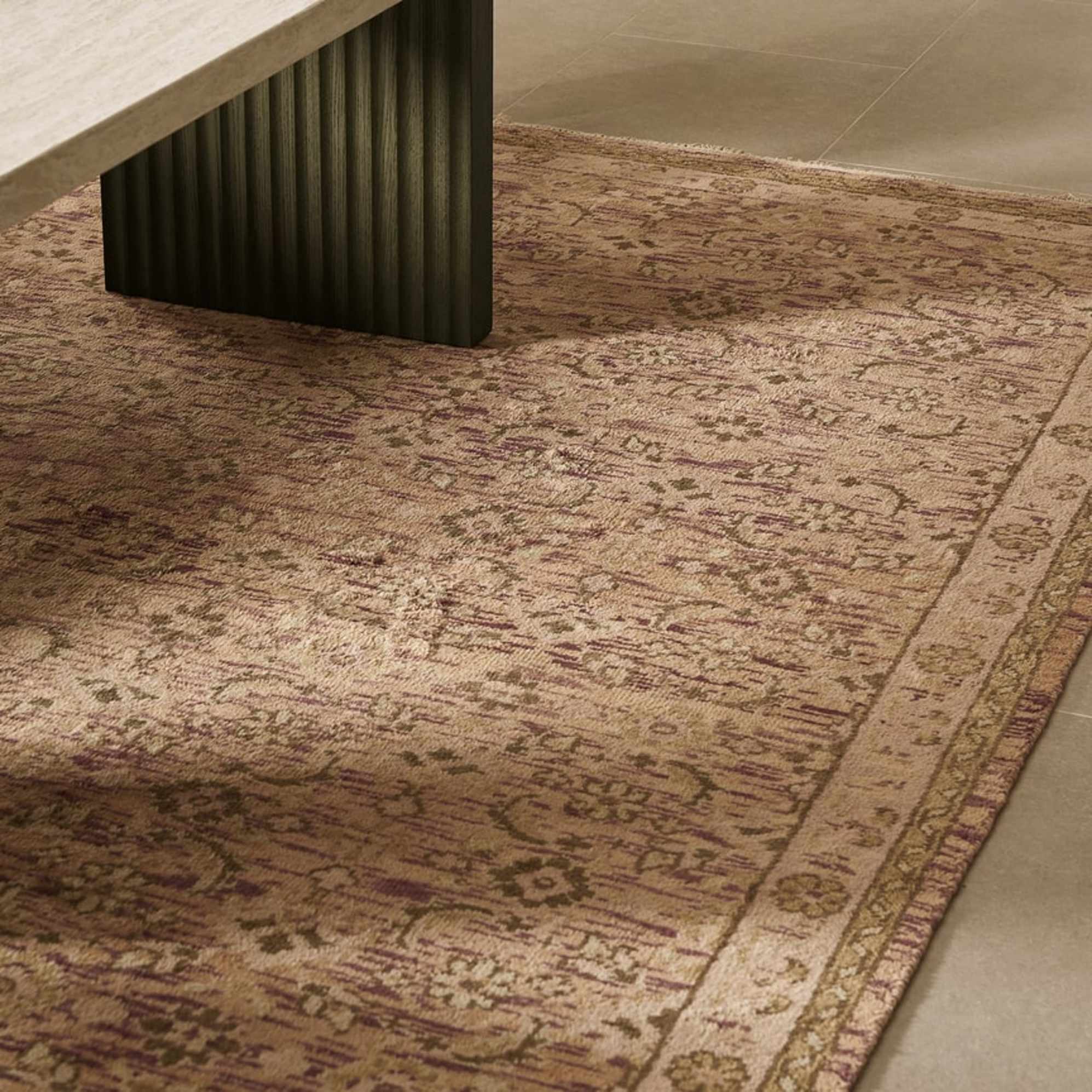 An abstract area rug in a light brown shade with tinges of maroon.