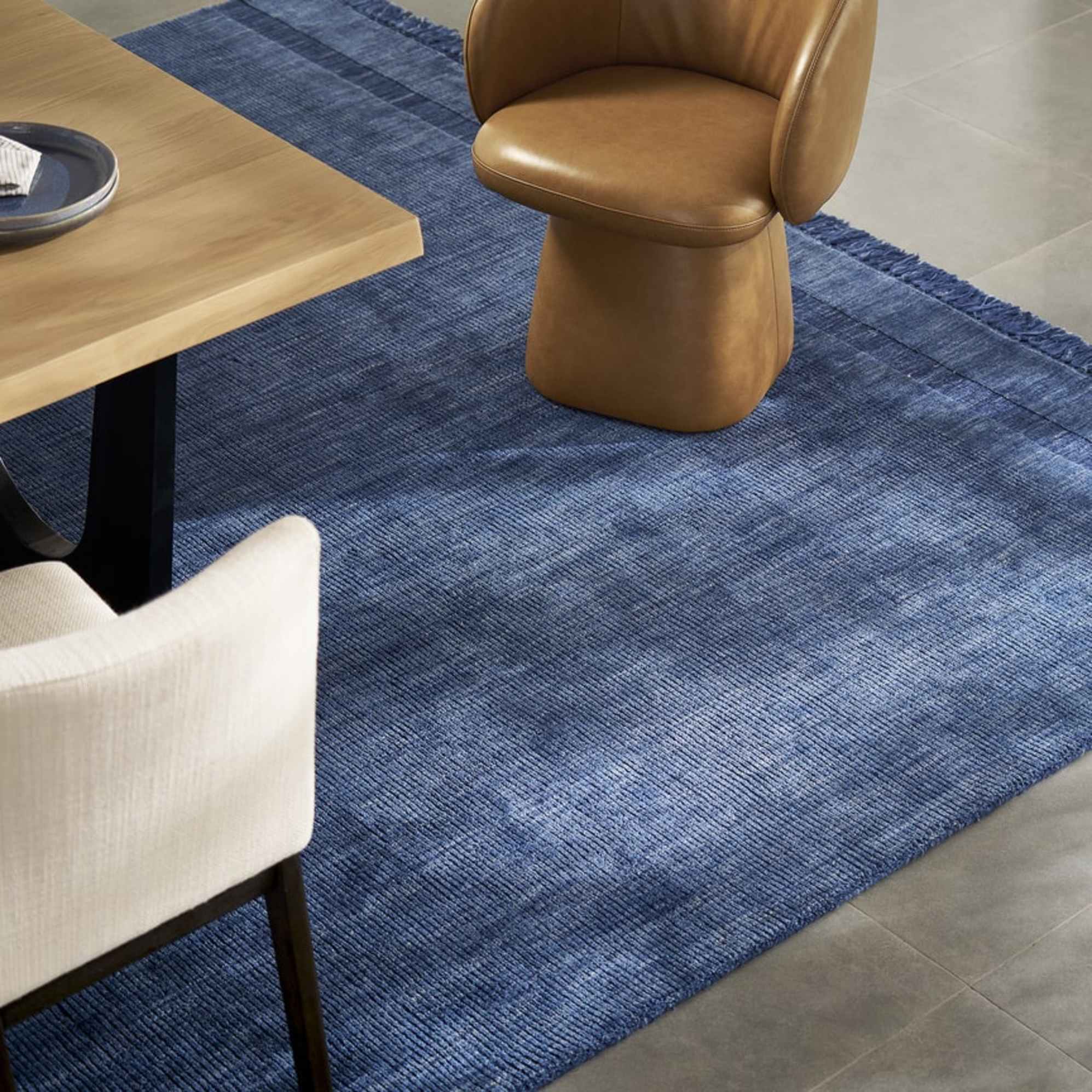 A dark blue wool area rug placed in a dining room under a dining table.