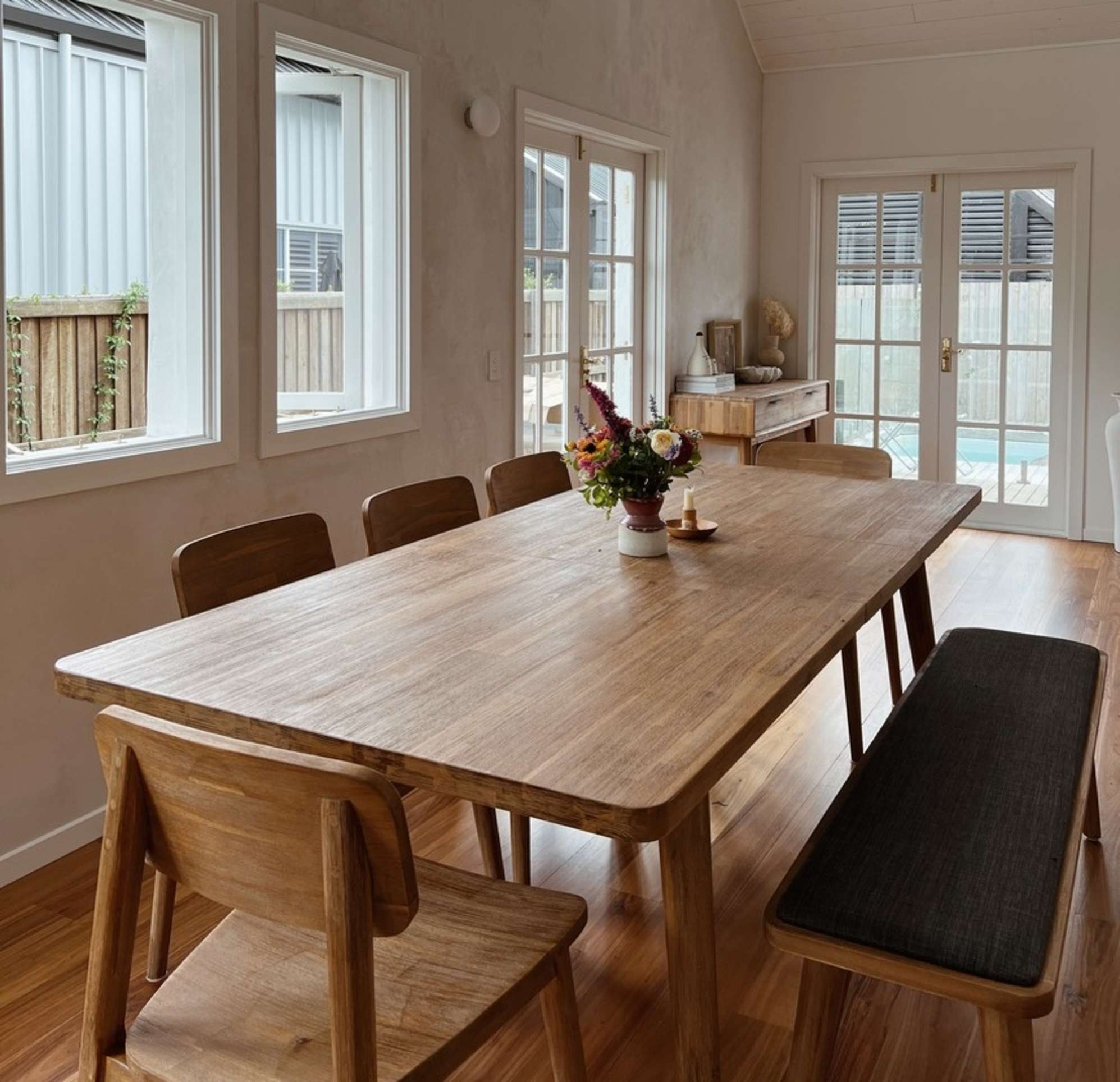 An acacia wood extendable dining table with matching chairs and a bench.
