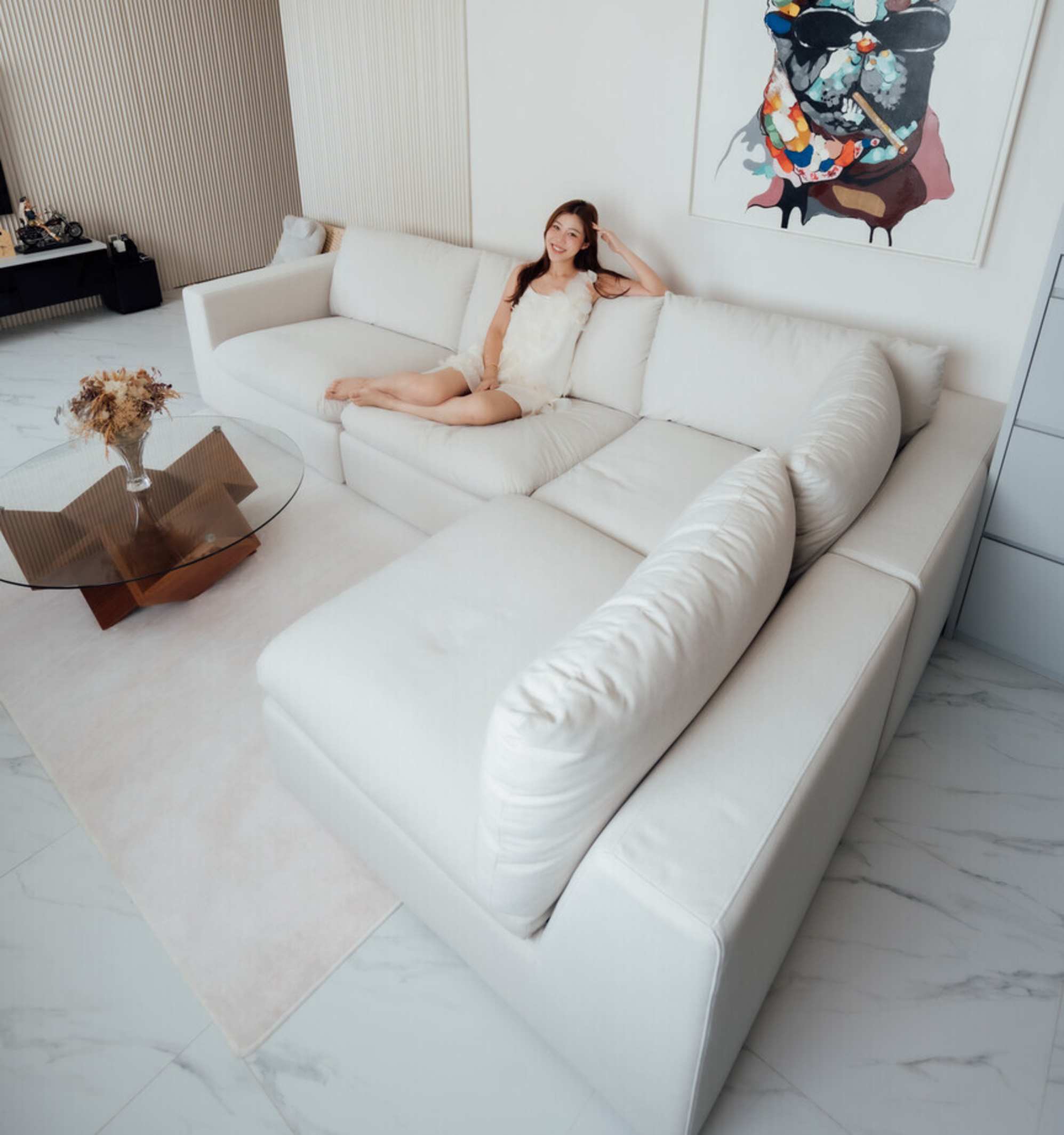 A person sitting on a sectional sofa placed in a living room.