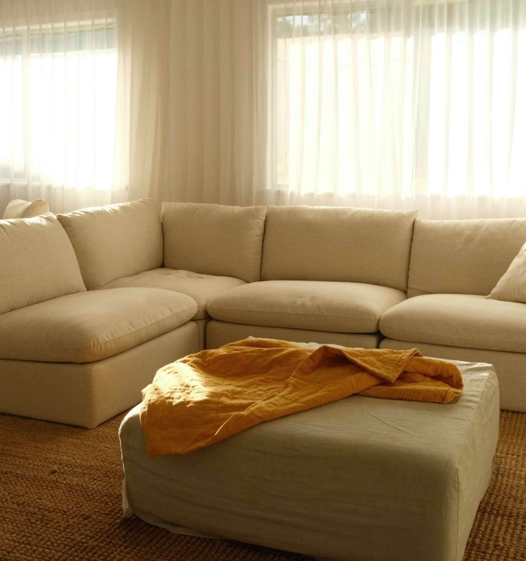 A chaise sectional sifa placed in a living room against sheer curtains.