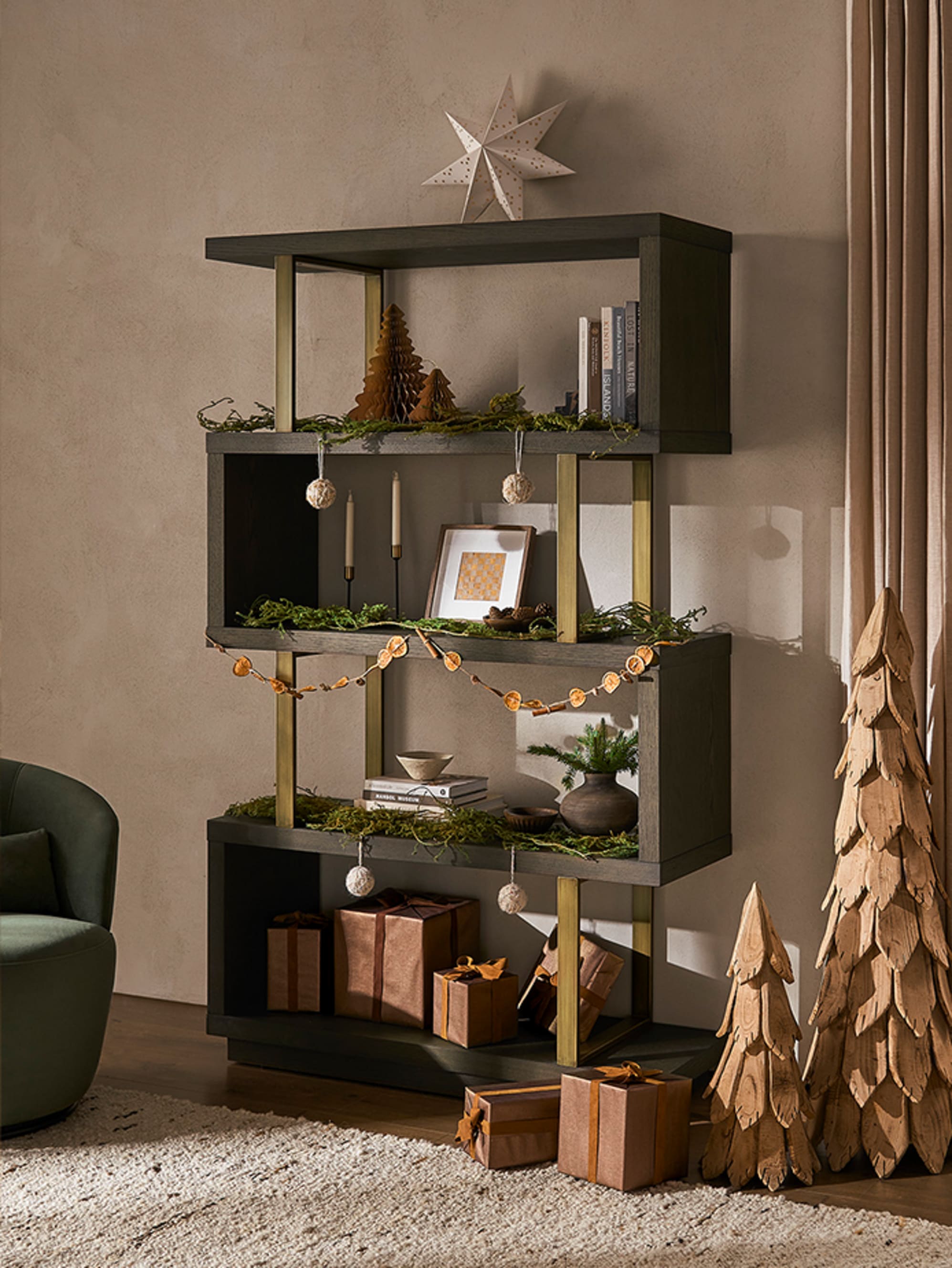 A 4-tier dark wood shelf with books, potted plants, frames, candles and Christmas decor on top.