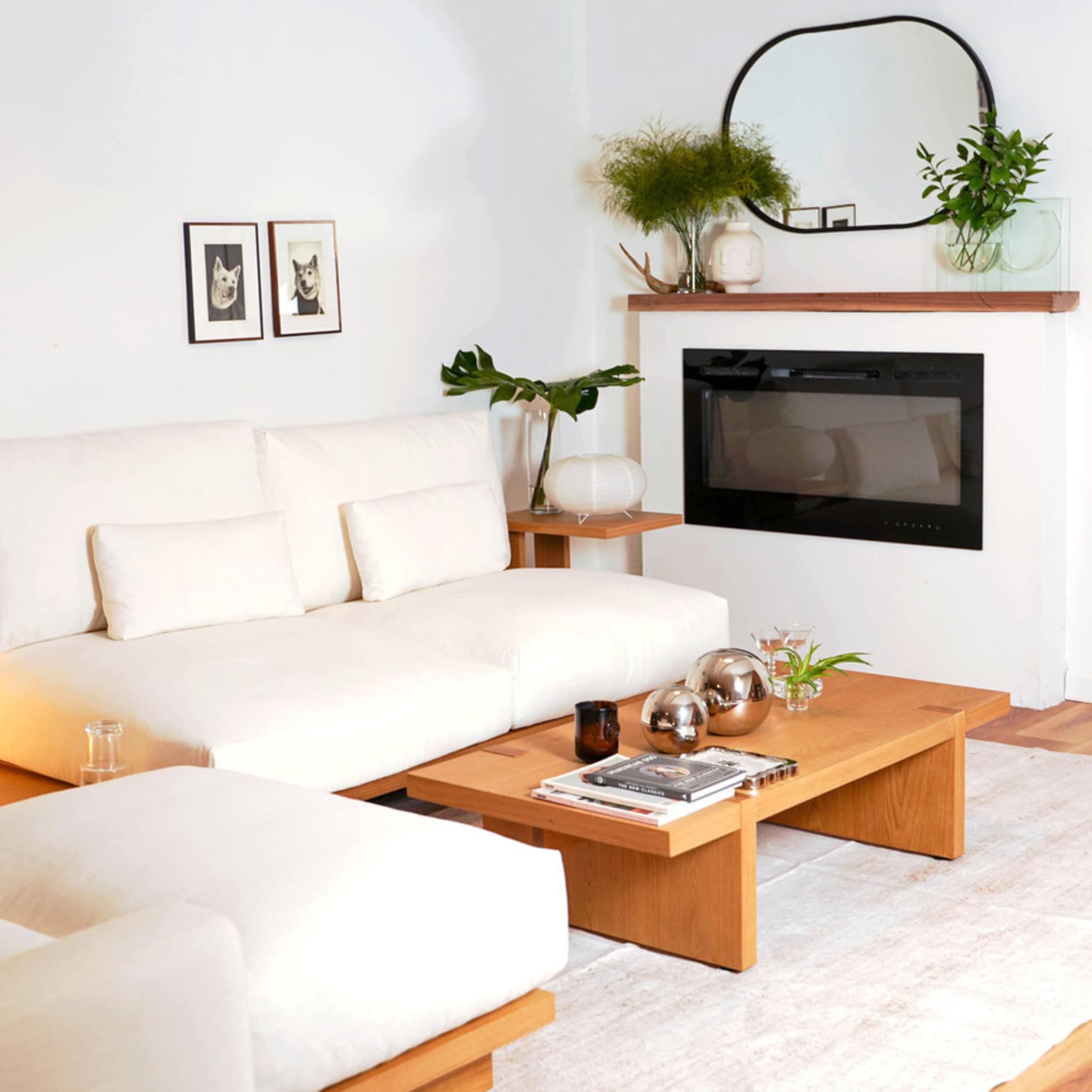 A wooden coffee table placed in a living room with a matching white modular sofa.