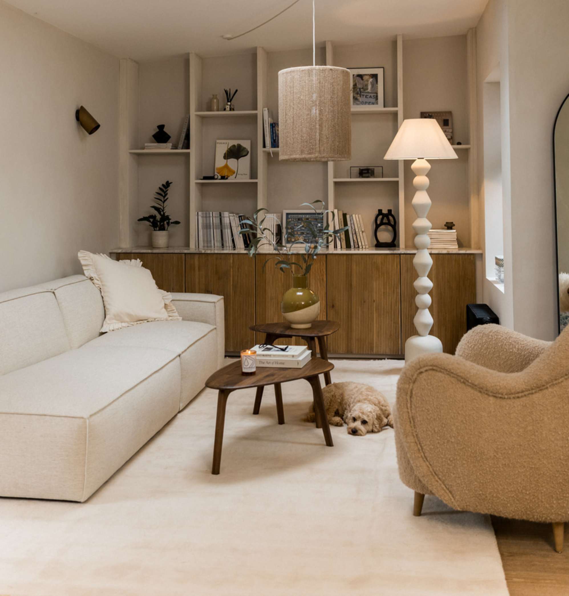 A dog sleeping beside a walnut nesting coffee table placed in the middle fo a living room.
