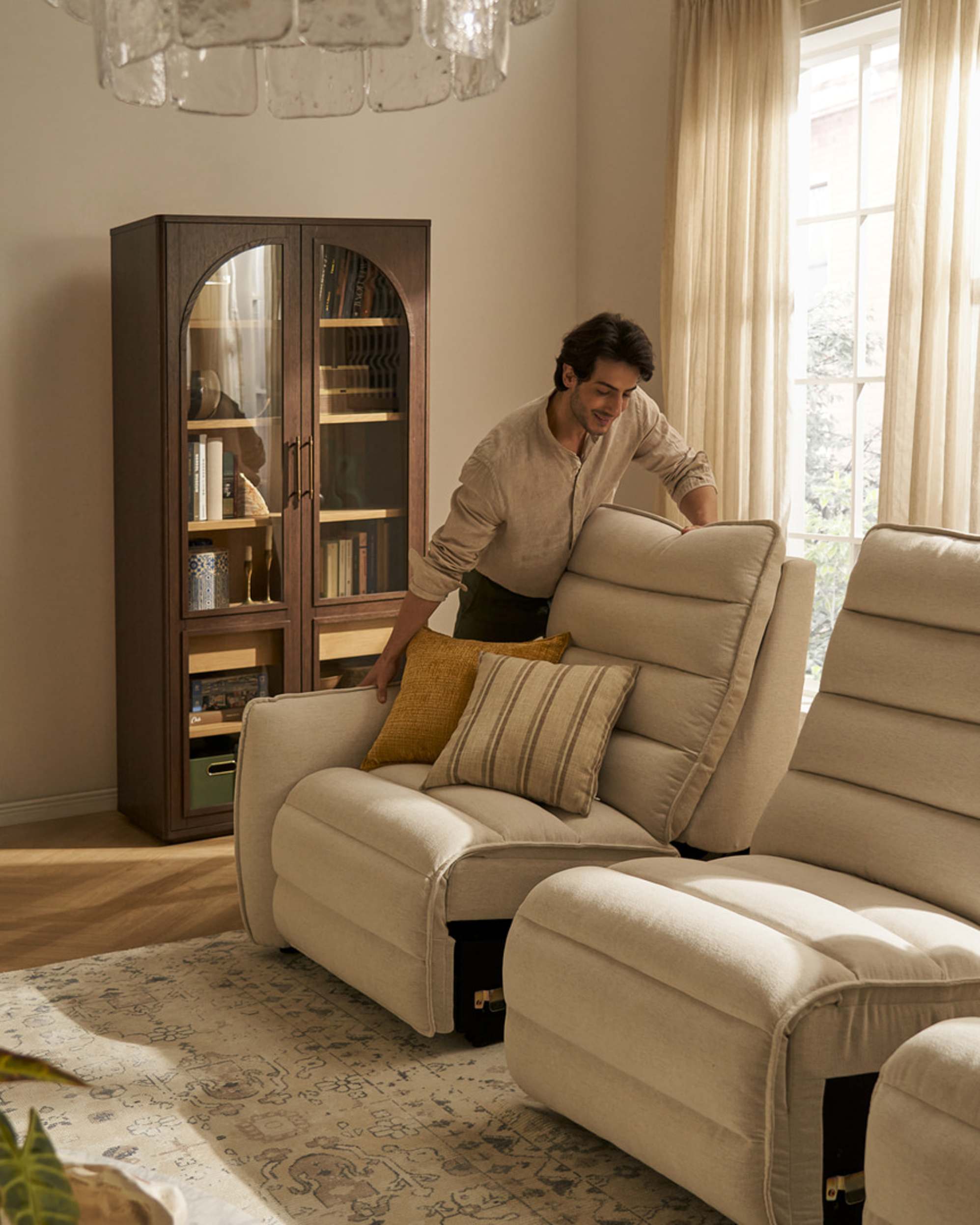 A person shifting a modular power recliner sofa together.