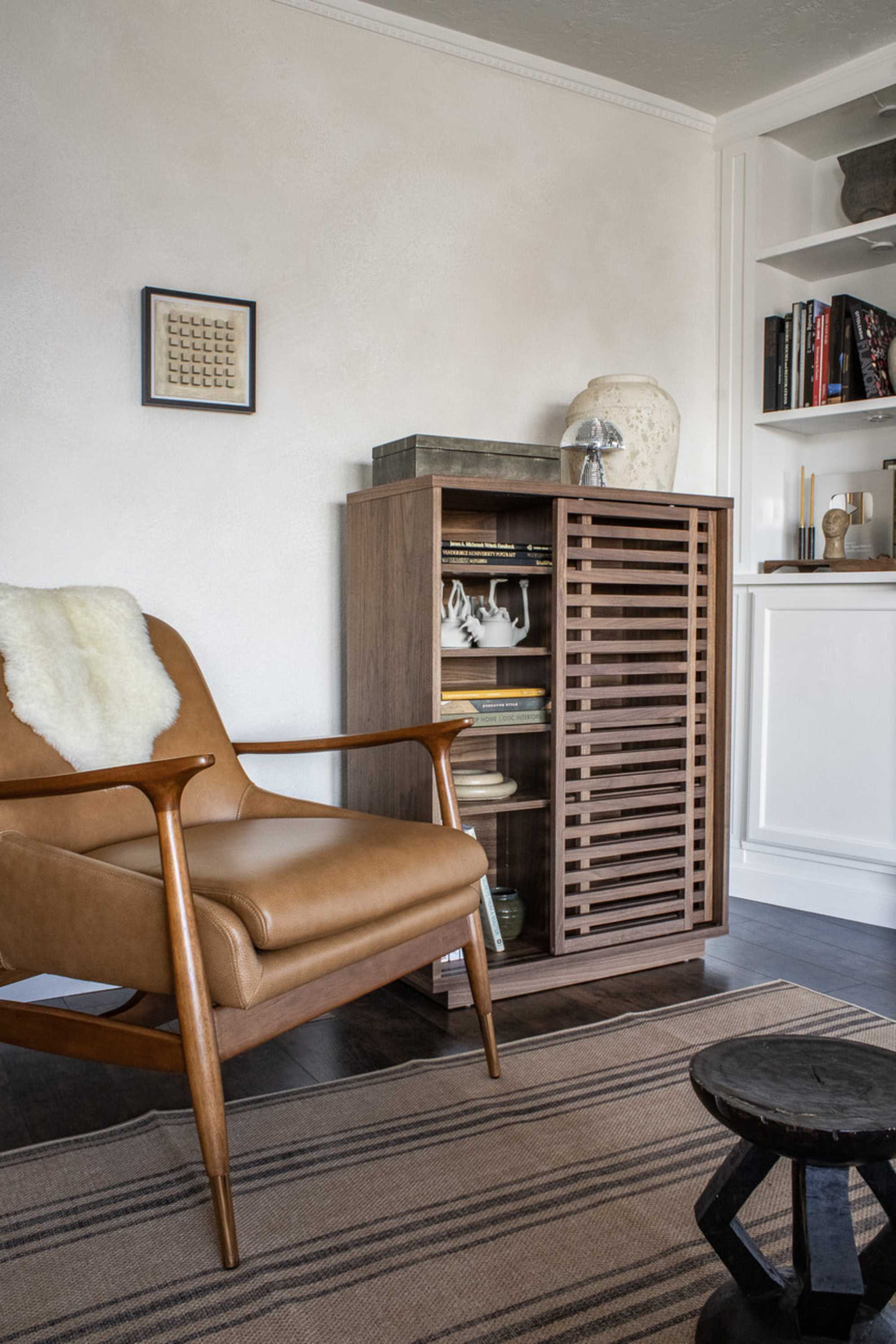 A leather armchair placed next to a wooden cabinet.