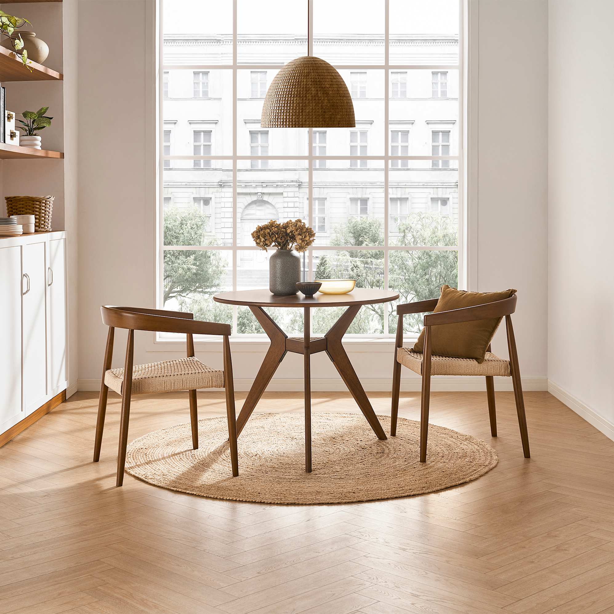 The Tribeca Round Dining Table in an apartment dining room, accompanied by 2 Austen Arm Chair in walnut
