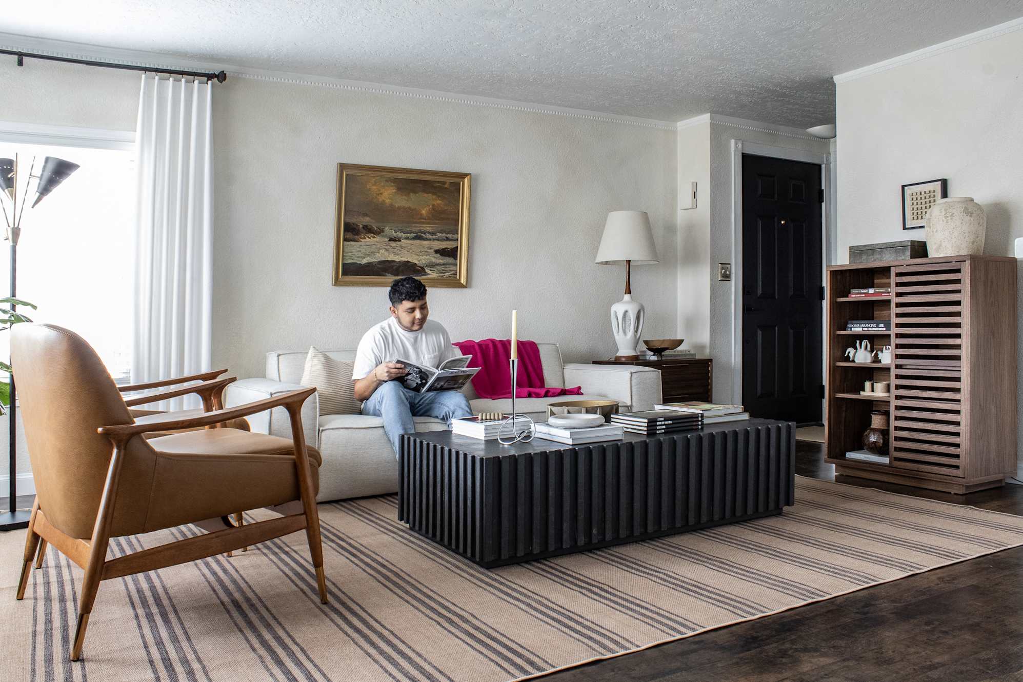 A man sitting on a sofa, reading a book.