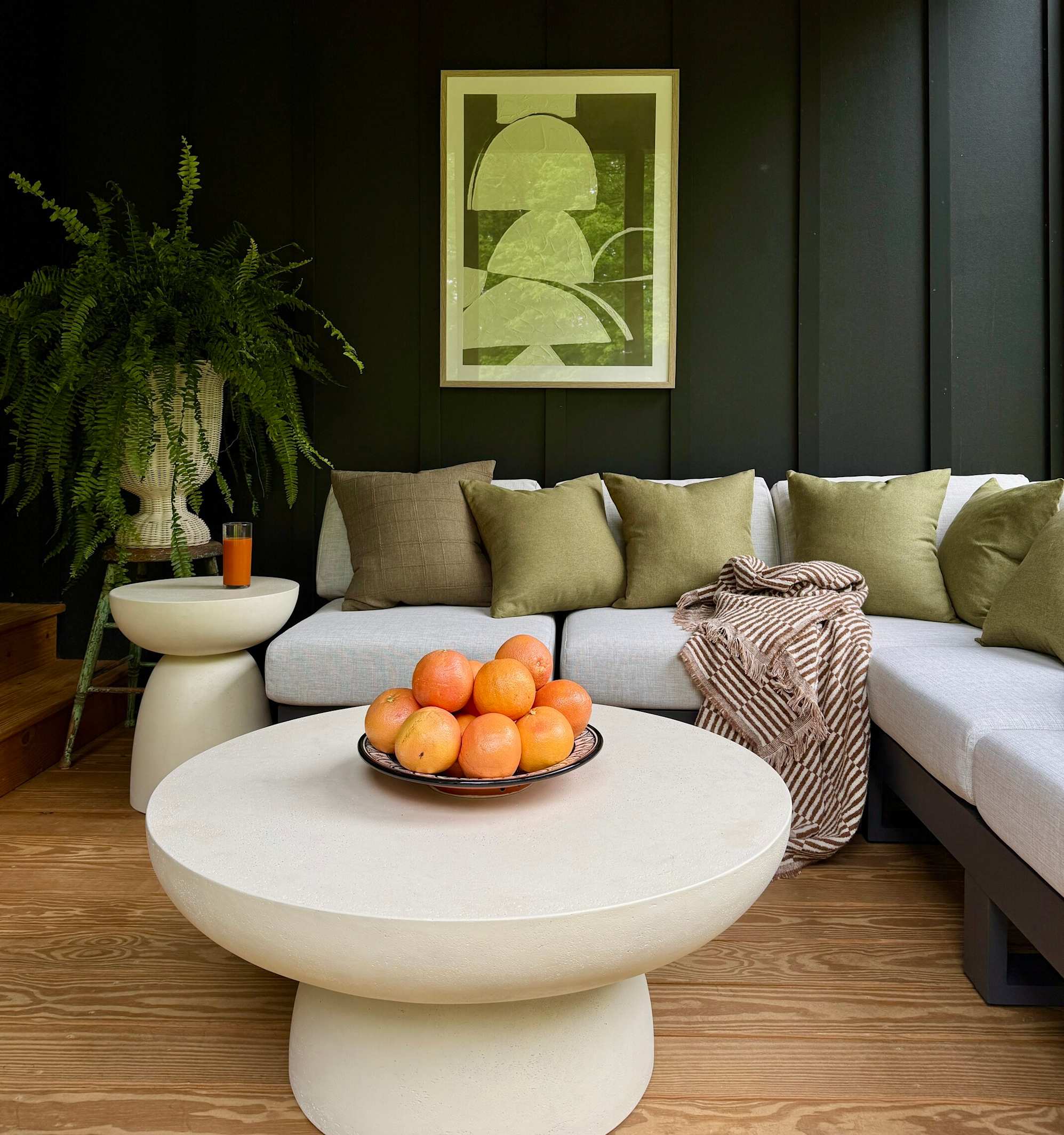 A white sofa with green pillows and a throw.