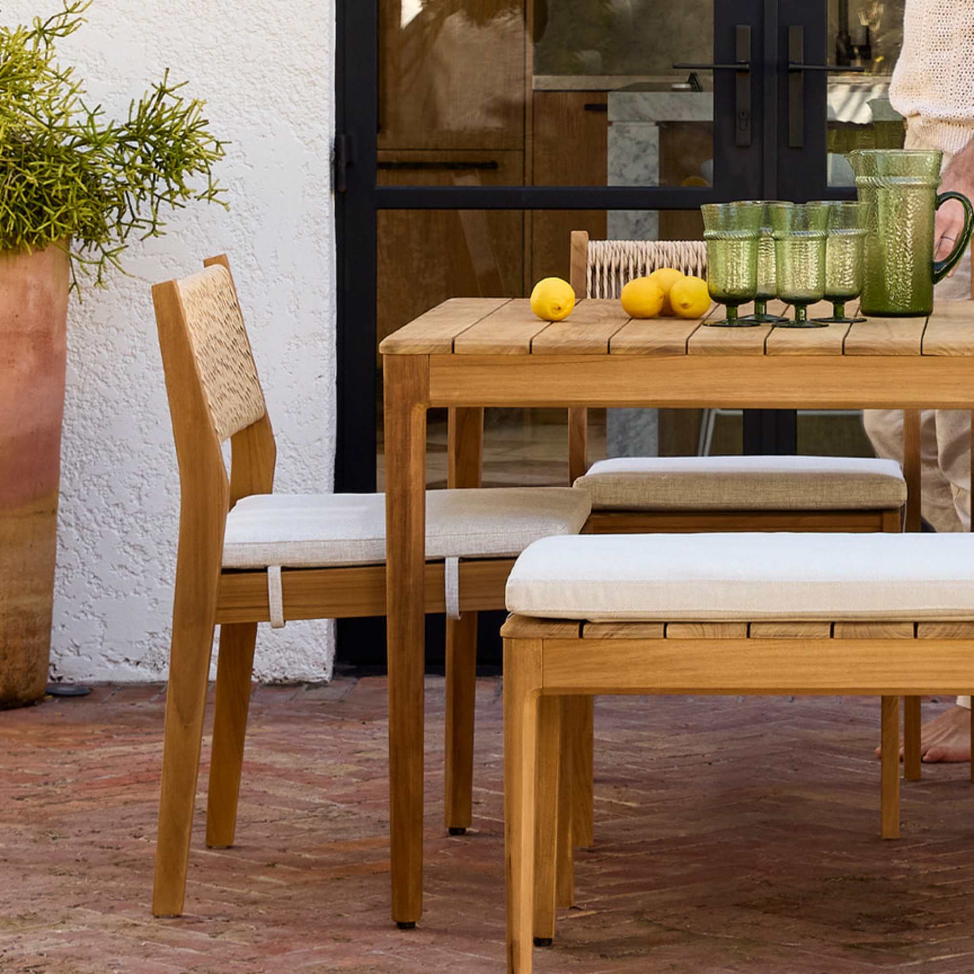 A teak dining table, matching dining chairs, and a bench.