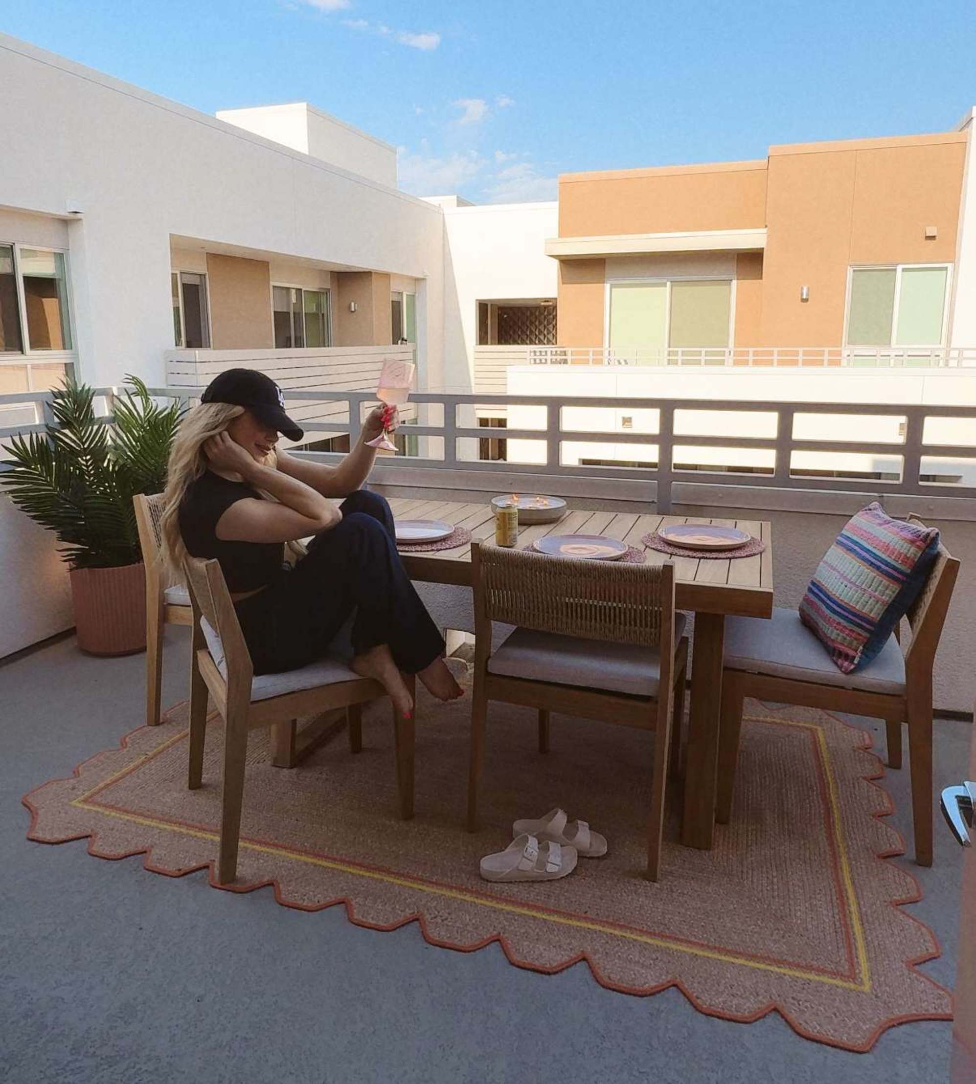  person sitting at a teak dining table set placed on a balcony.