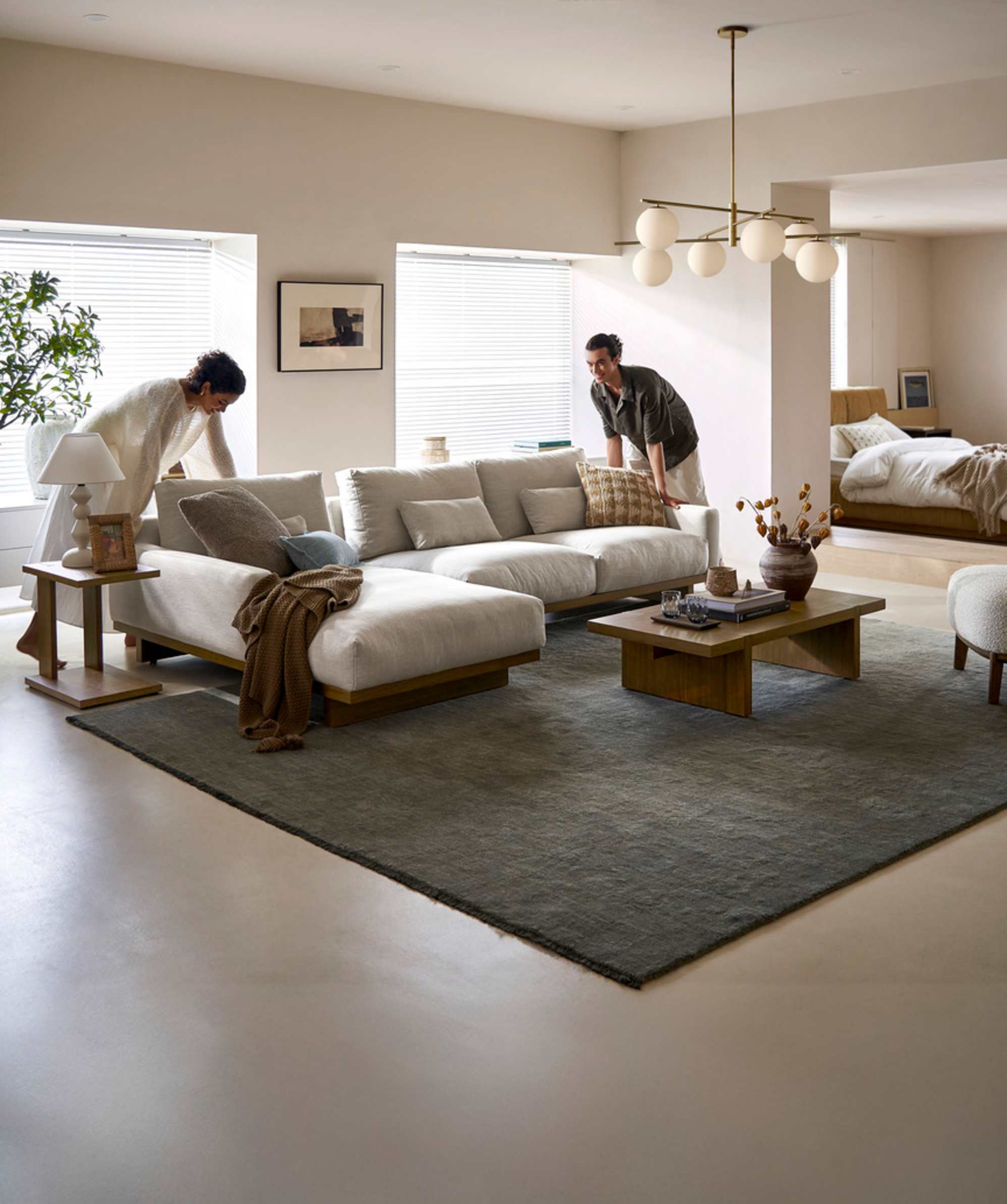 Two people moving a modular sofa in a living room.