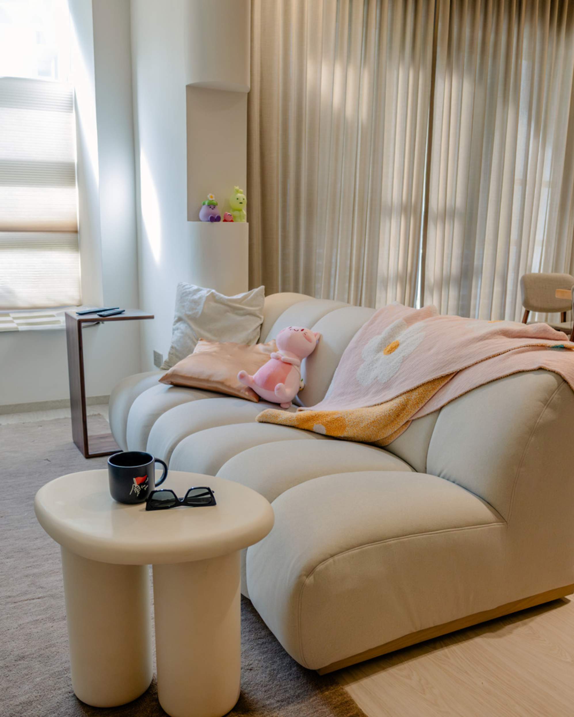 An armless two seater sofa with a round side table placed beside it.