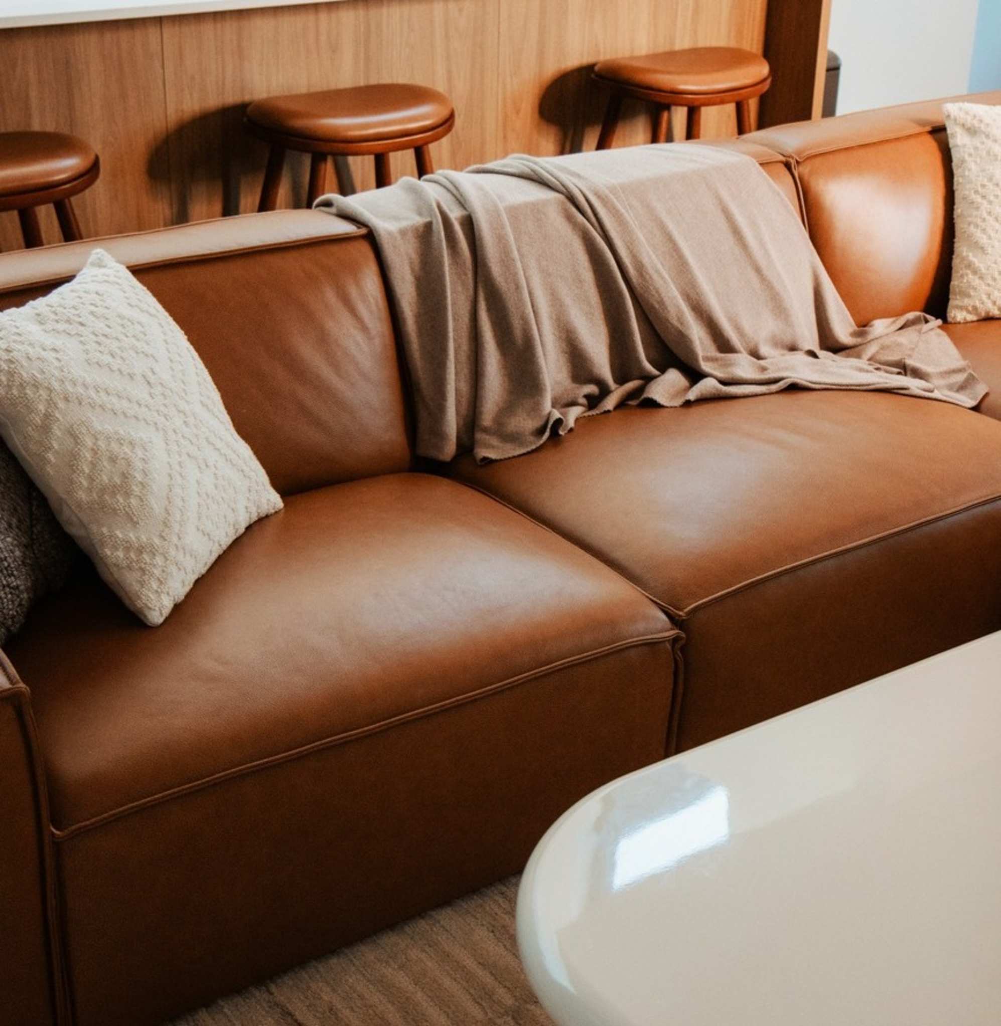 A leather extended sofa with a beige throw and accent cushions.