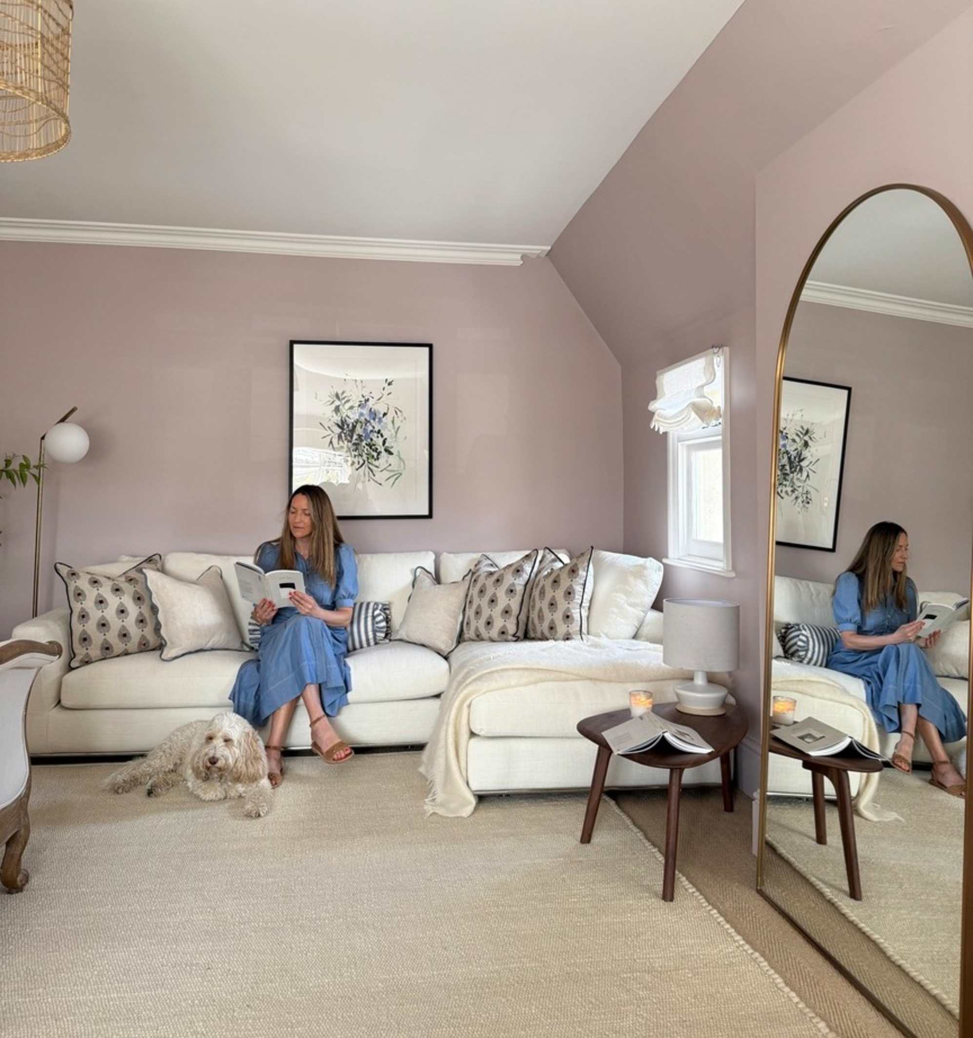 A person reading a book while sitting on a white chaise sectional sofa placed in the corner of a room.