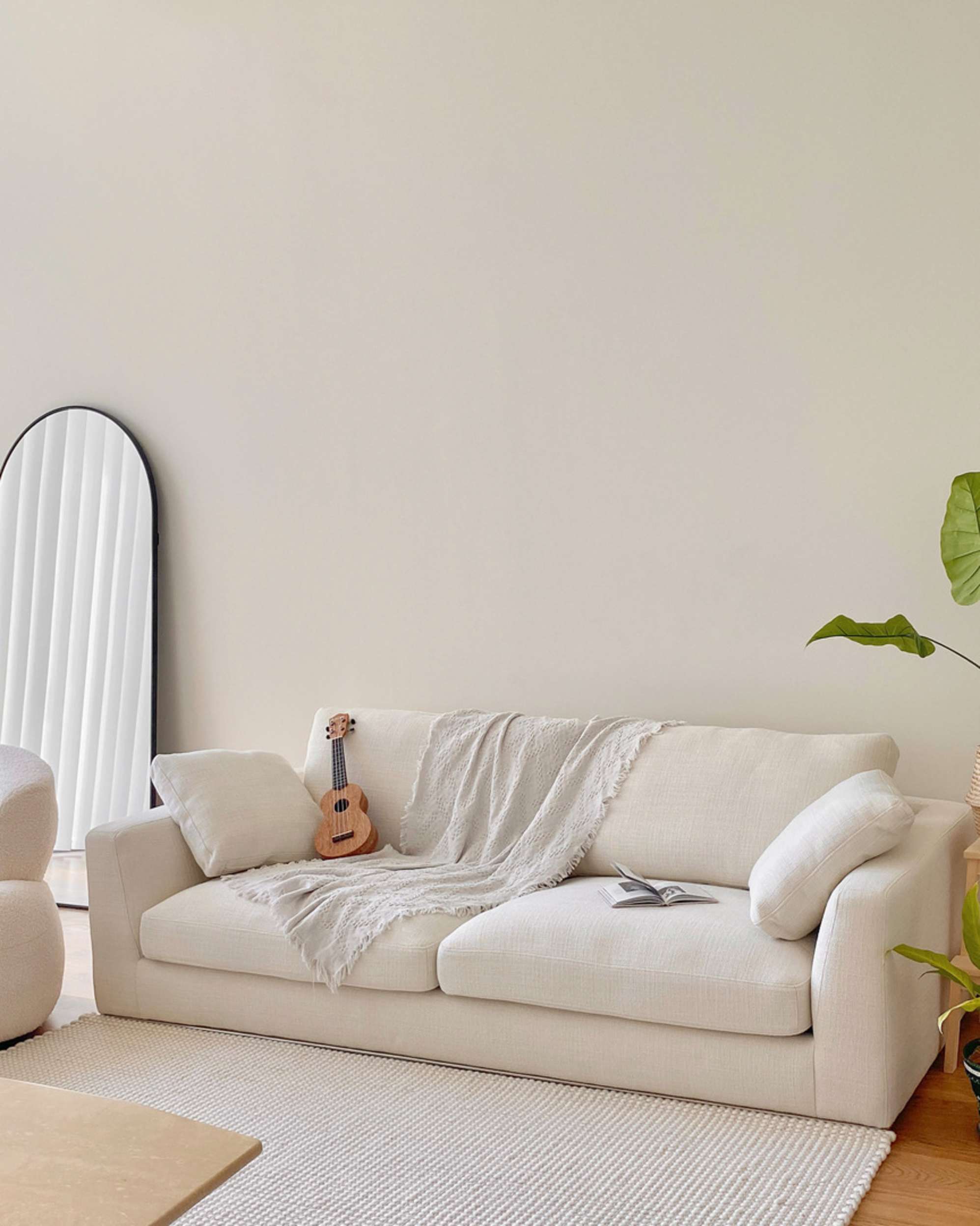 A white two-seater sofa placed against a beige wall.