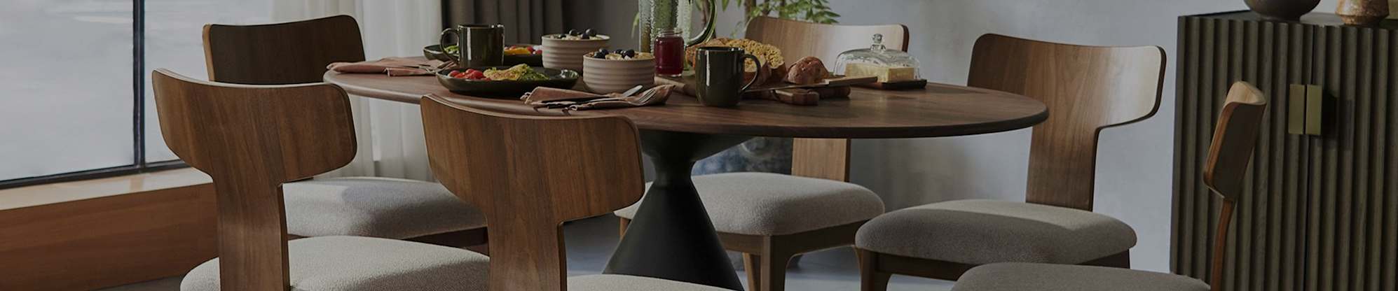 An oval wooden dining table with 6 dining chairs with curved backs.