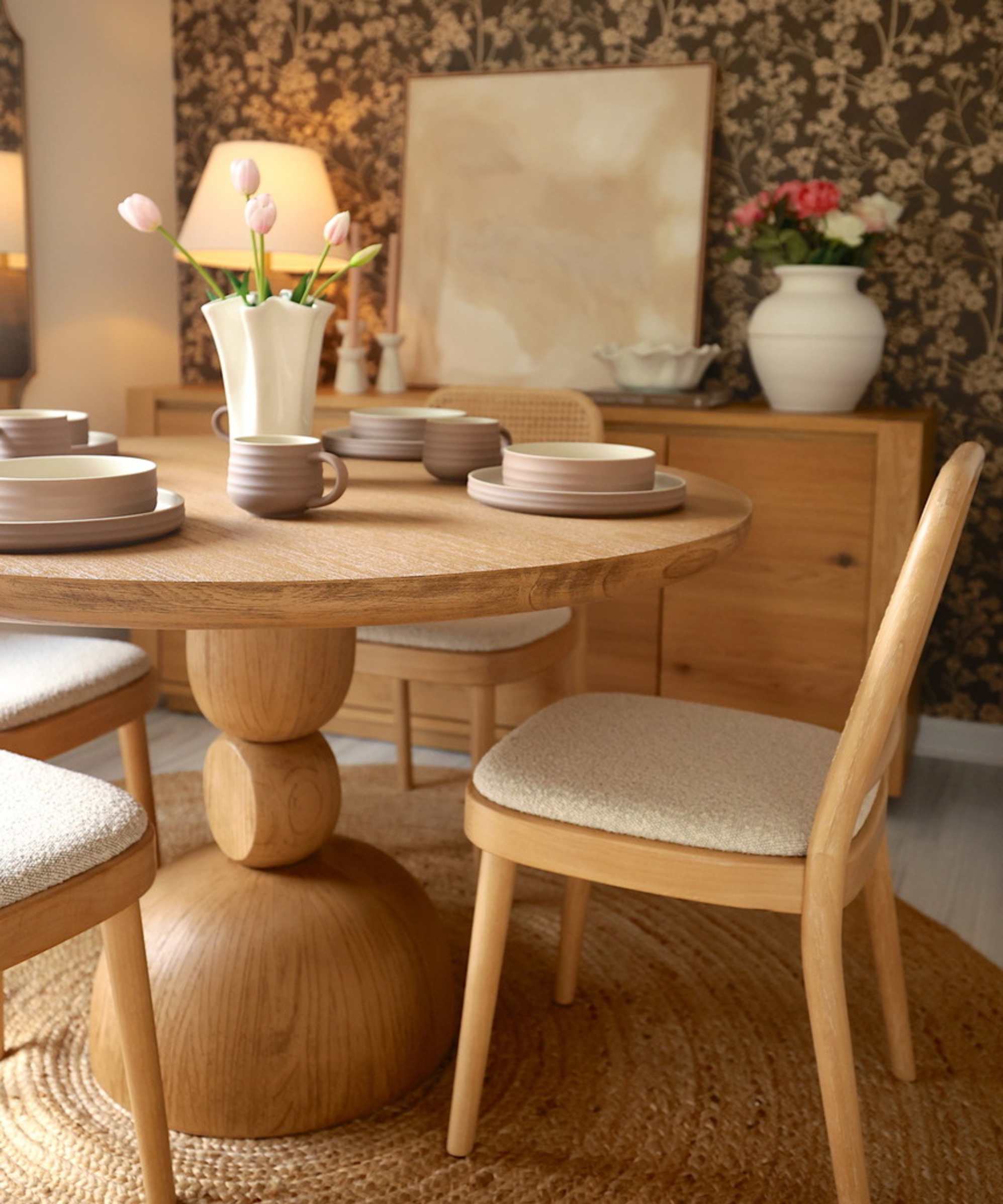 A round wooden dining table with four upholstered cane chairs.