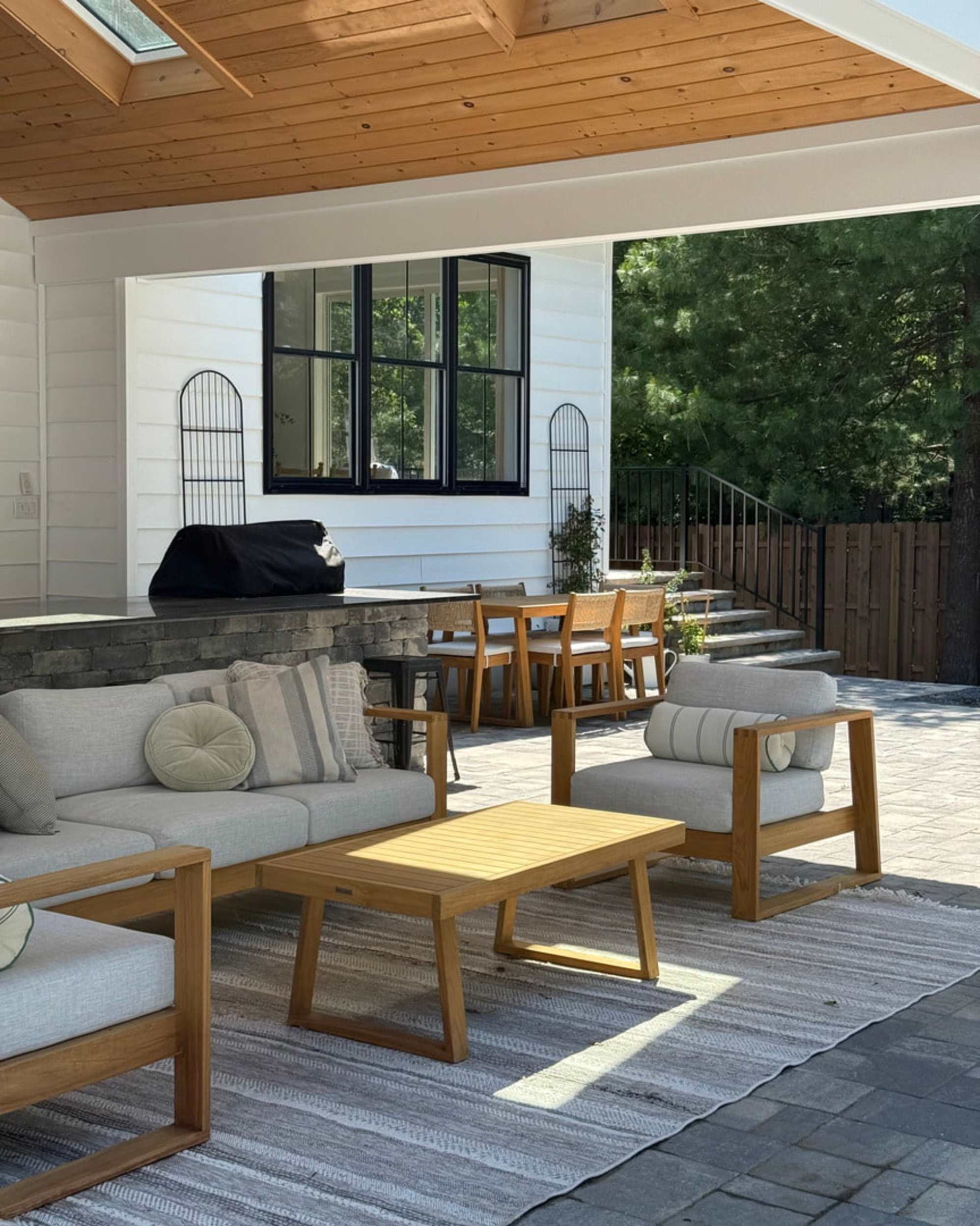 A teak outdoor lounge set placed in the backyard under a sheltered area.