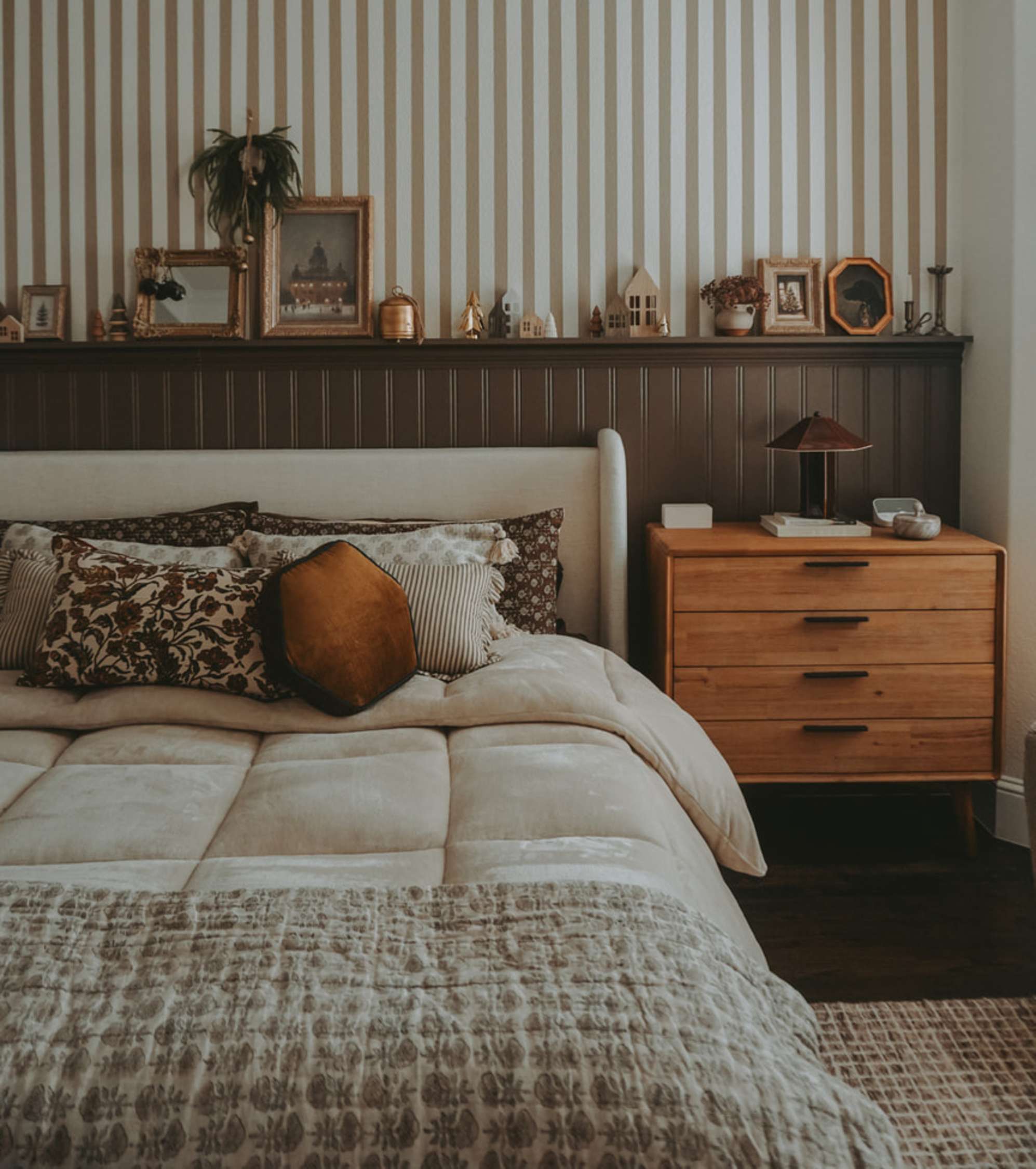 An acacia wood 4-drawer dresser placed beside a bed with a wingback headboard.