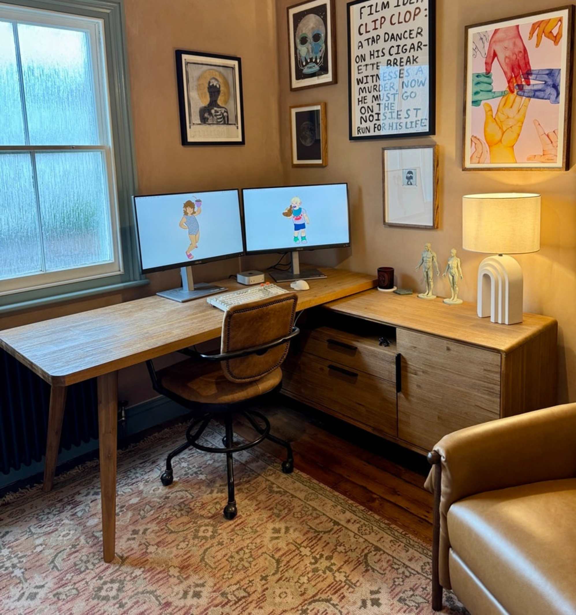 An acacia wood L-shaped desk placed in the corner by a window with two monitors propped up on the tabletop.