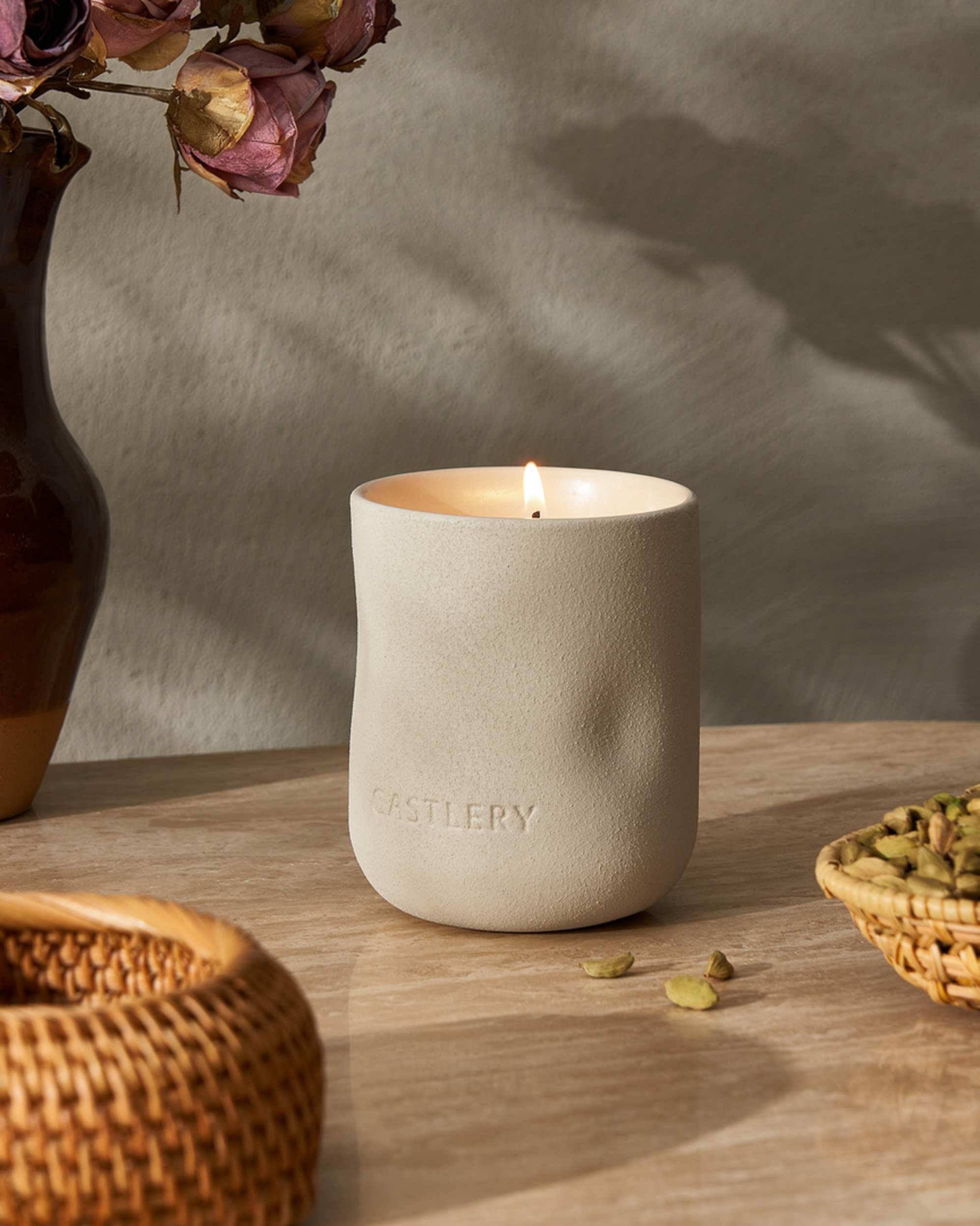 A candle placed on a table with a small lighted flame.