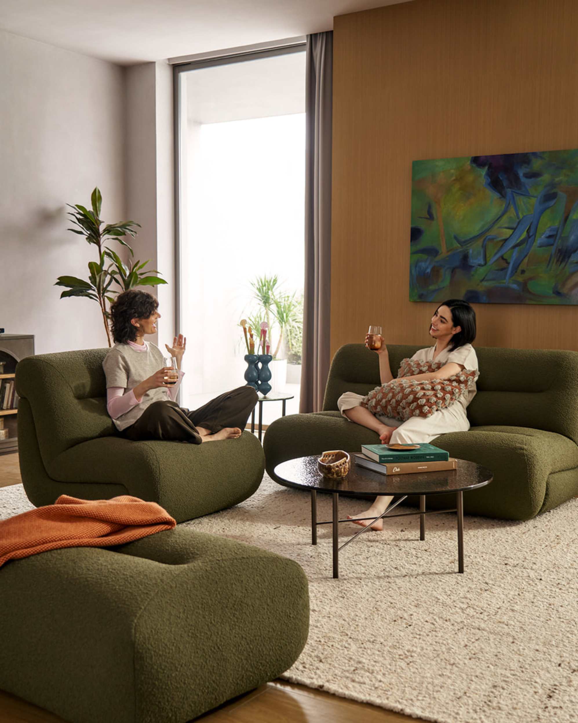 Two people sitting in the living room with glasses of drinks in hand while talking.