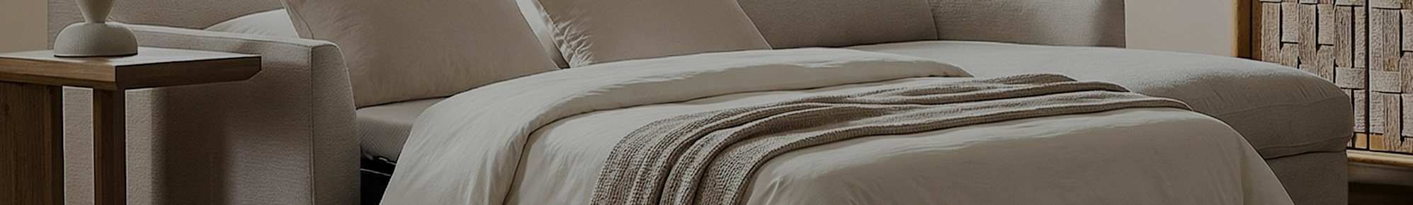 A sofa extended into a bed with white sheets and a brown throw.