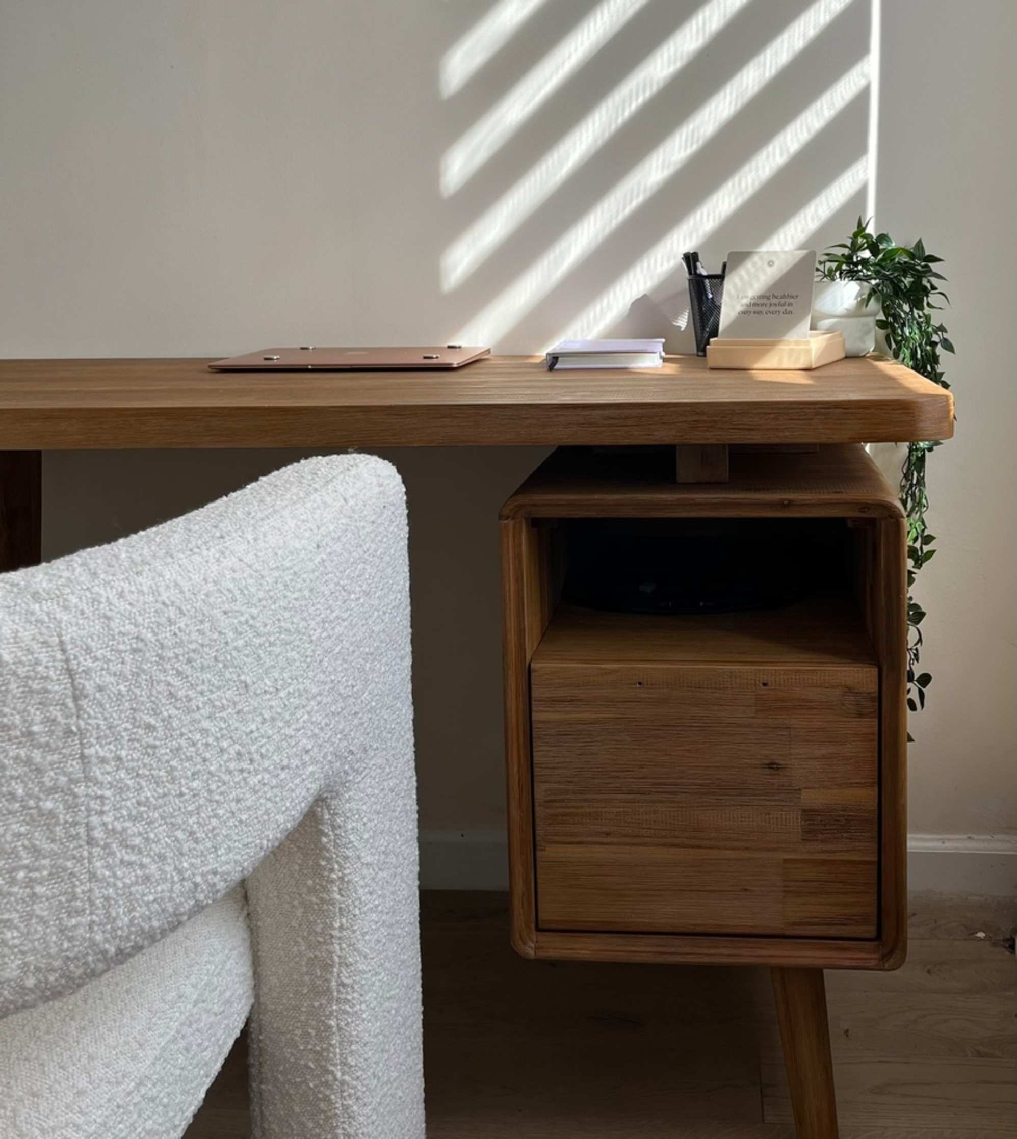 An acacia wood desk with built-in storage placed against a wall.