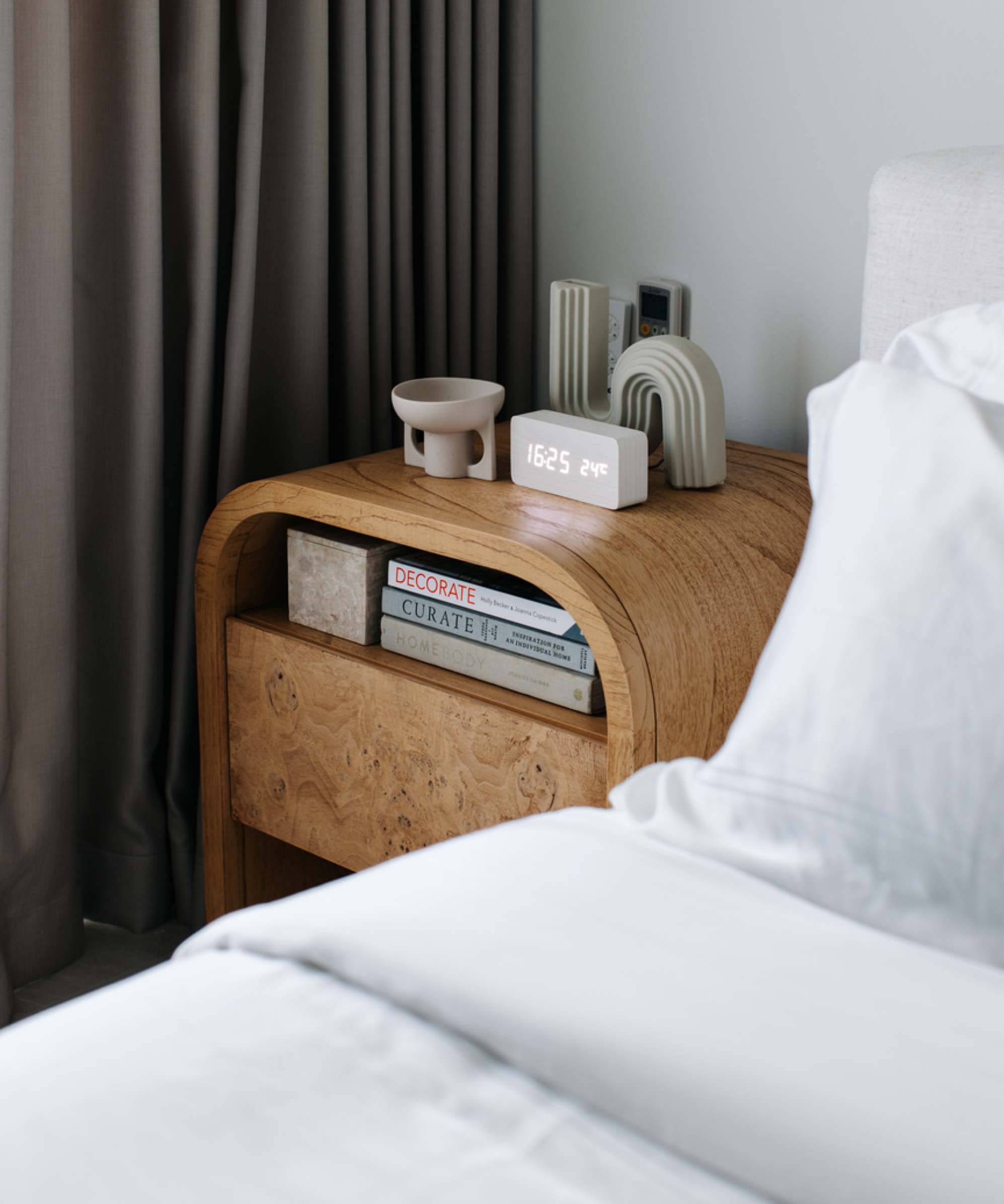 A mindi wood nightstand with books and decor placed on it. 