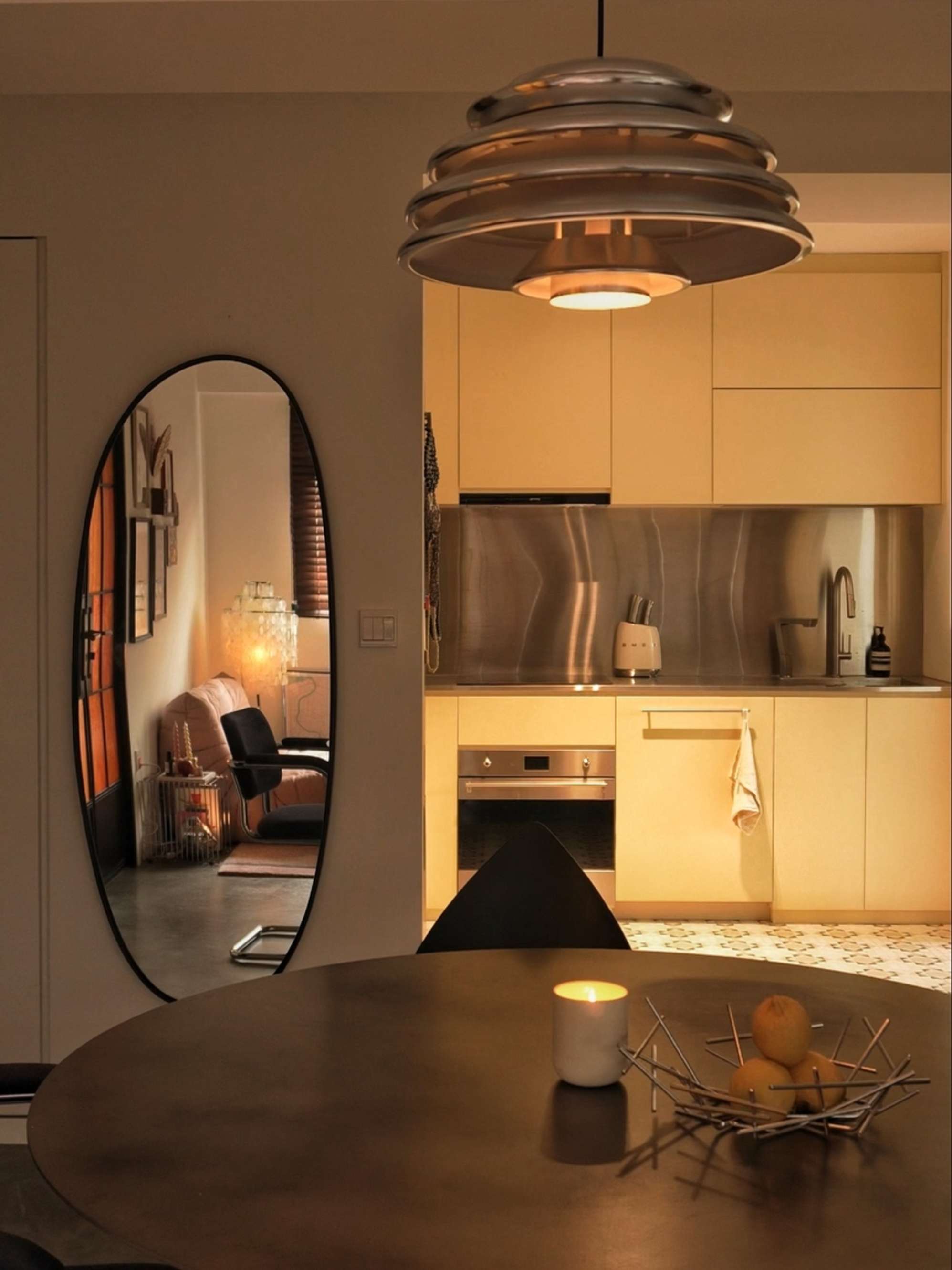 A round wooden dining table with a pendant lamp hanging above it.