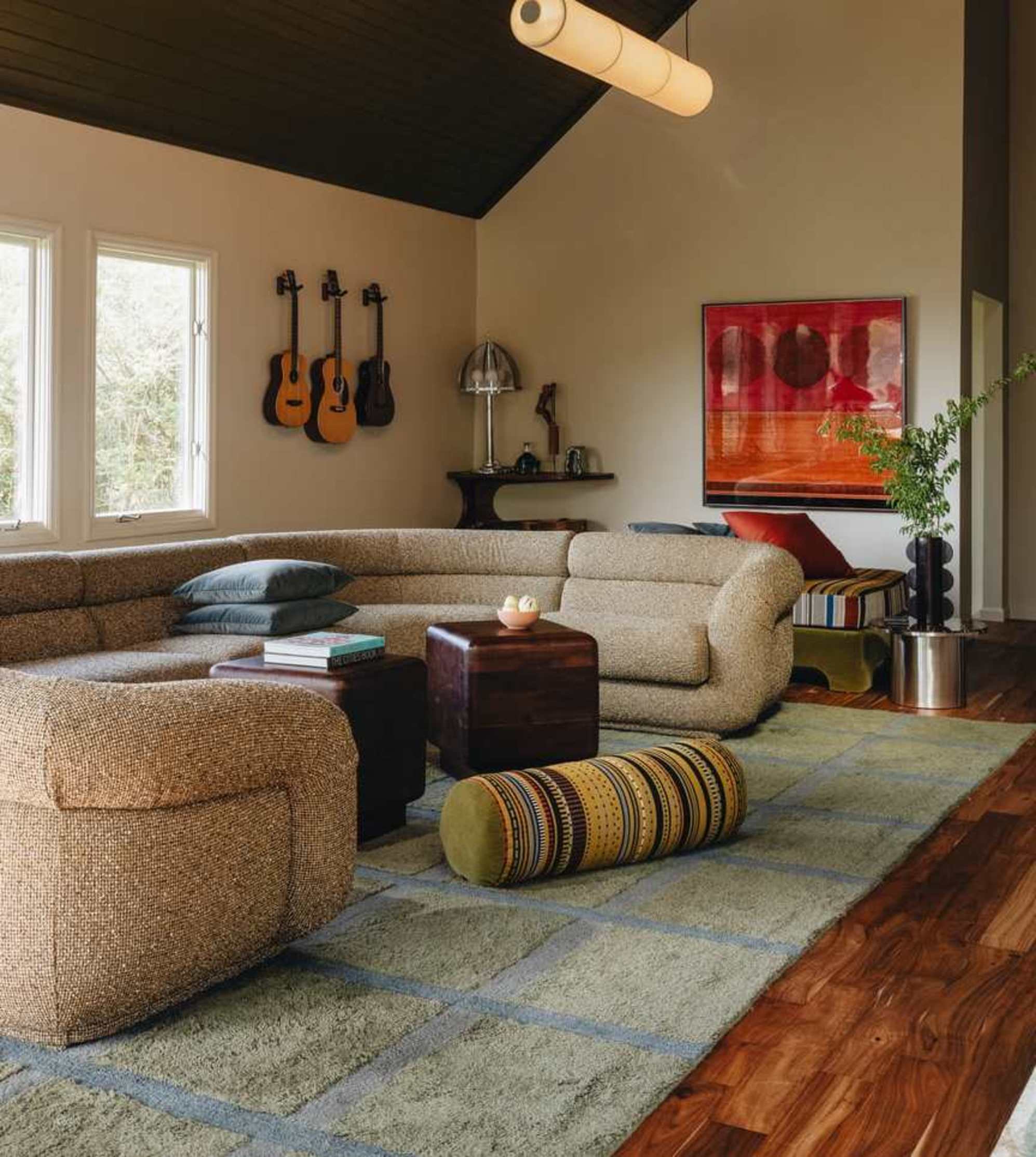 An L-shaped sectional sofa in a dark green placed in a living space with a sloped wooden ceiling.