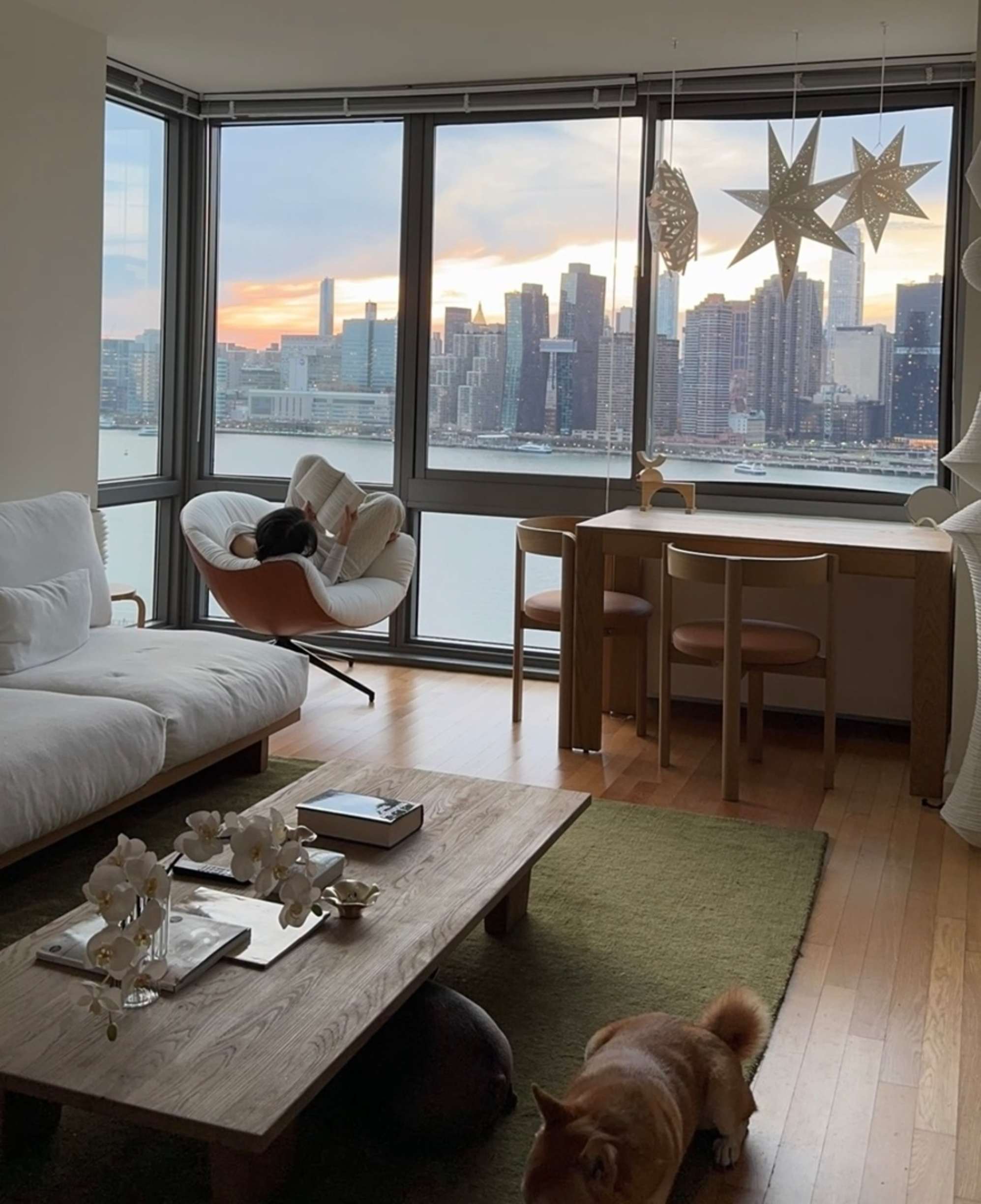 A person sitting on a performance fabric swivel armchair in her living room while facing the city skyline.