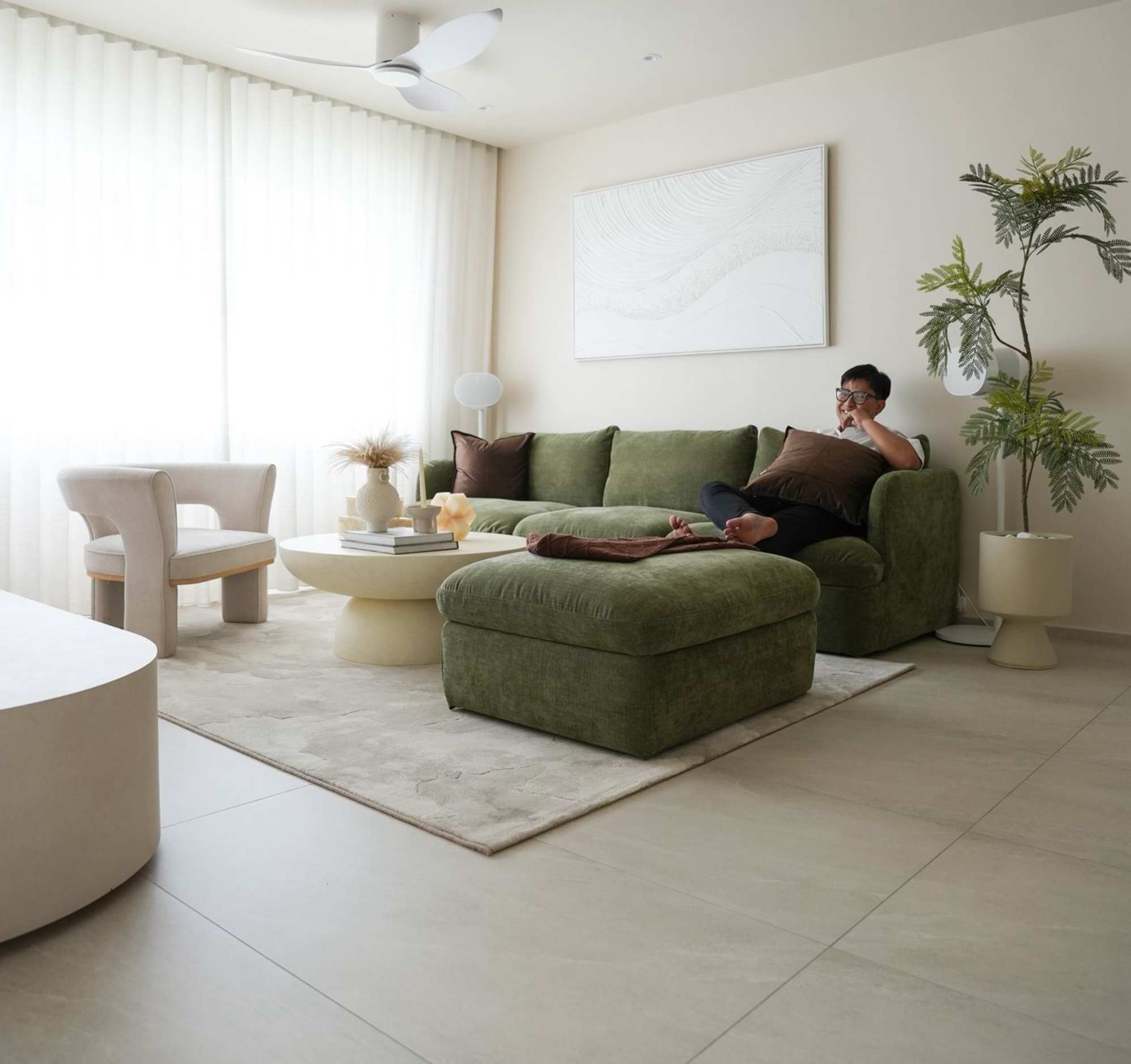 A person sitting on a dark green storage sofa with his legs up on an ottoman.