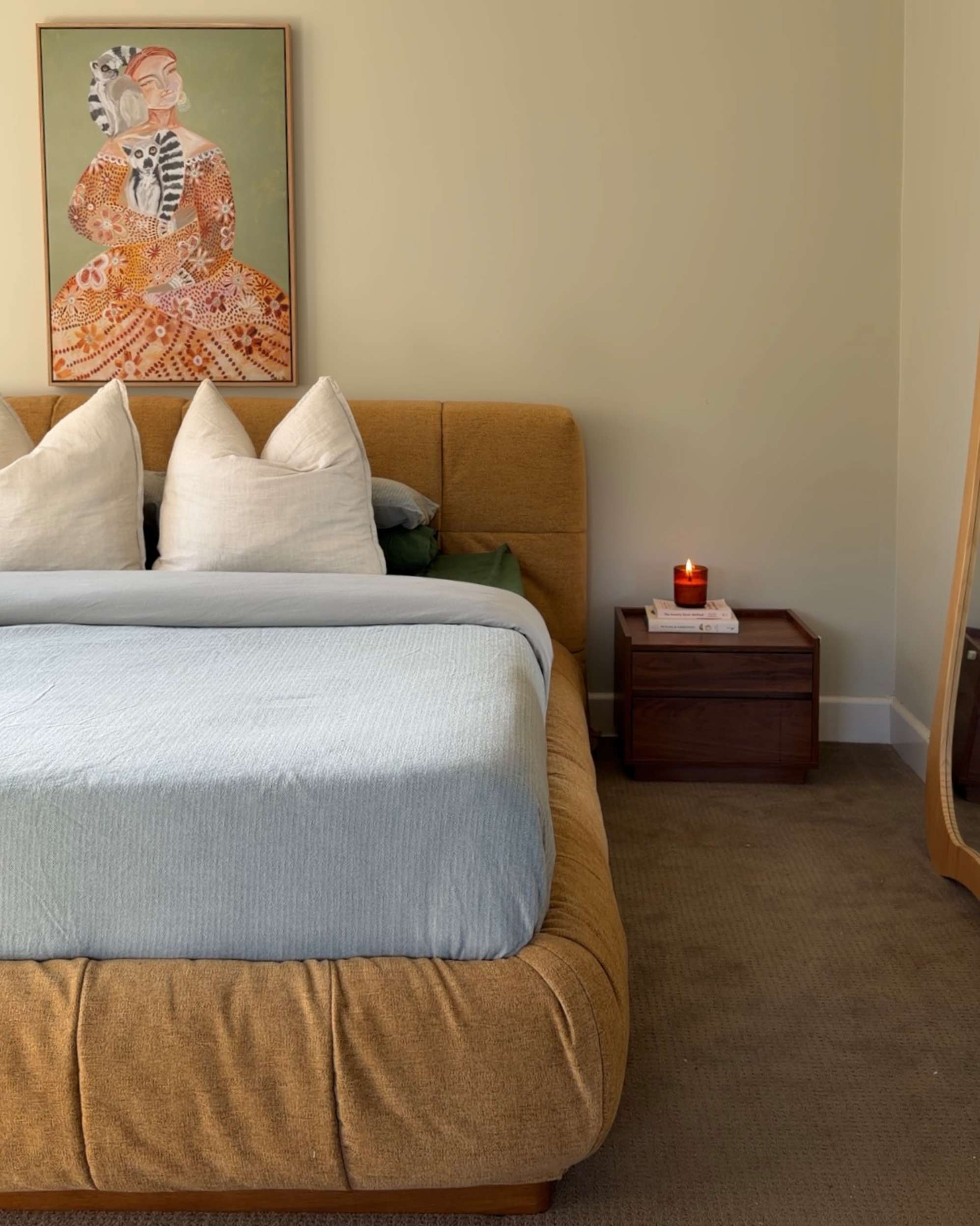 An upholstered storage bed with a wooden bedside table