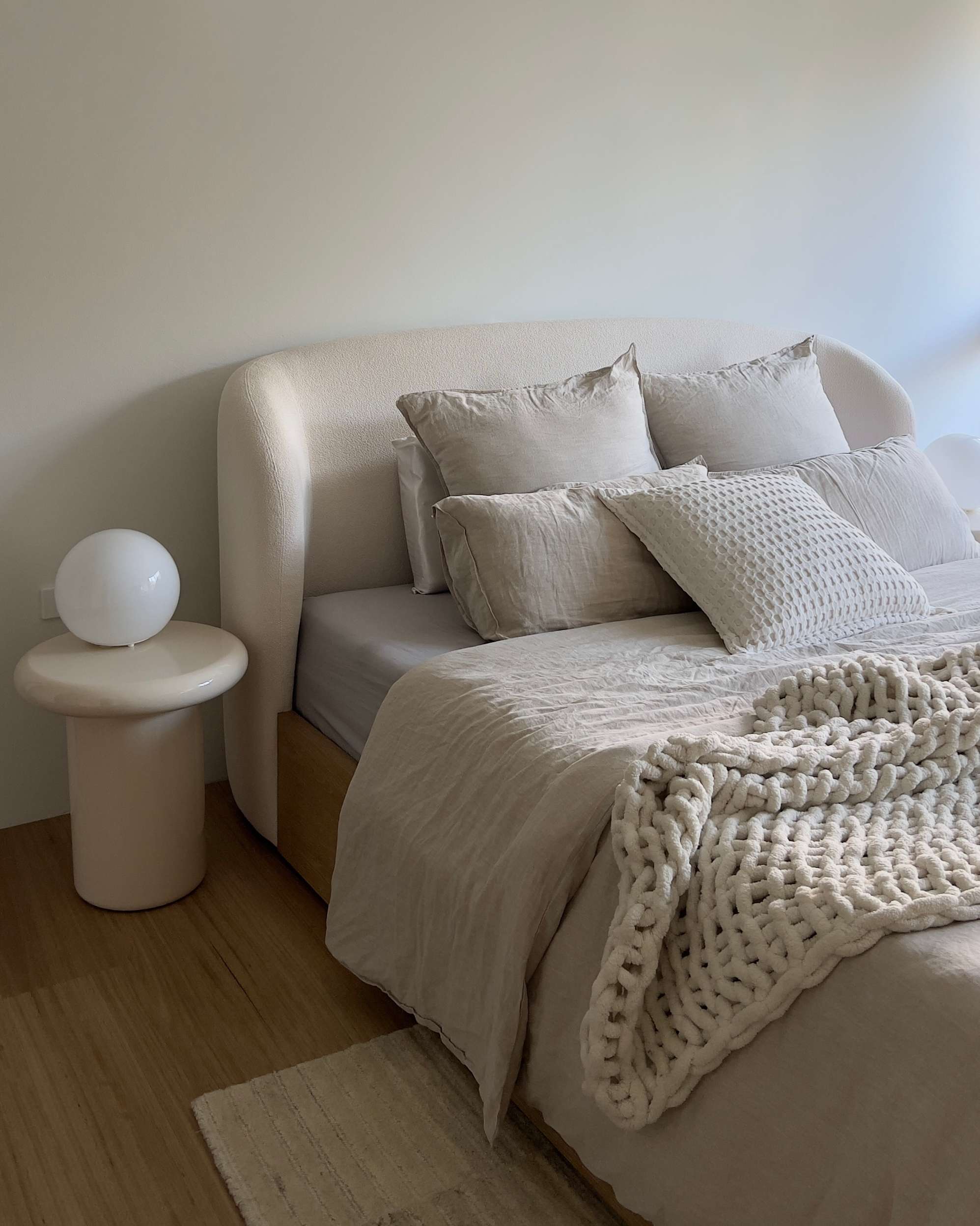 A bed with a cream headboard and a bedside table