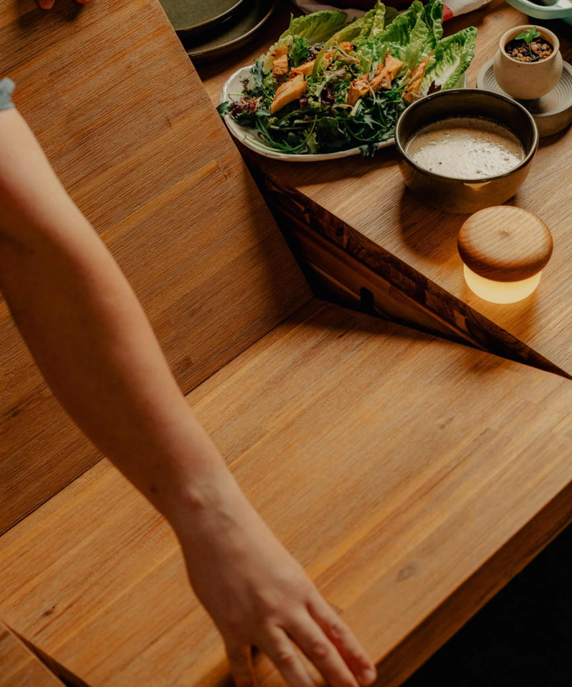 A person extending a wooden dining table.