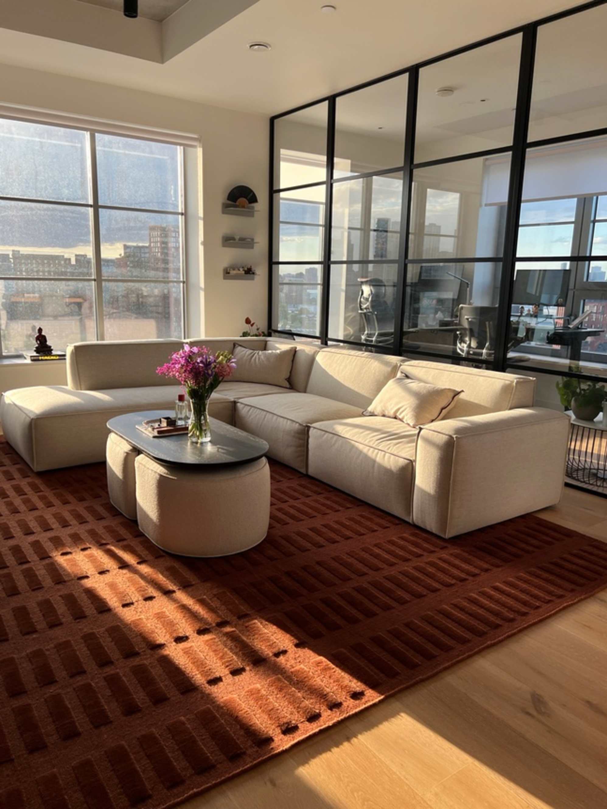 An extended side chaise sectional sofa placed atop a brick red area rug with a nesting coffee table. 