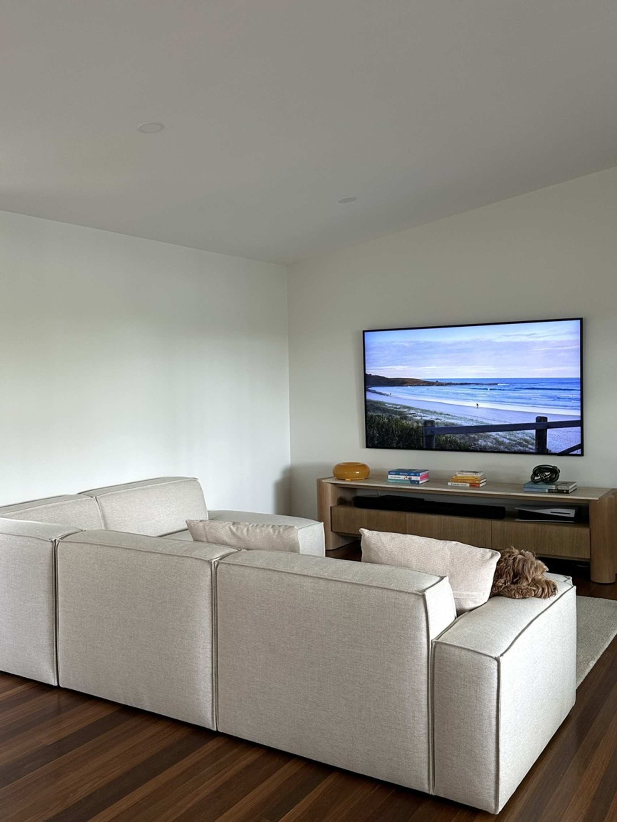 An extended side chaise sectional sofa placed in a living room to face a TV mounted on the wall.